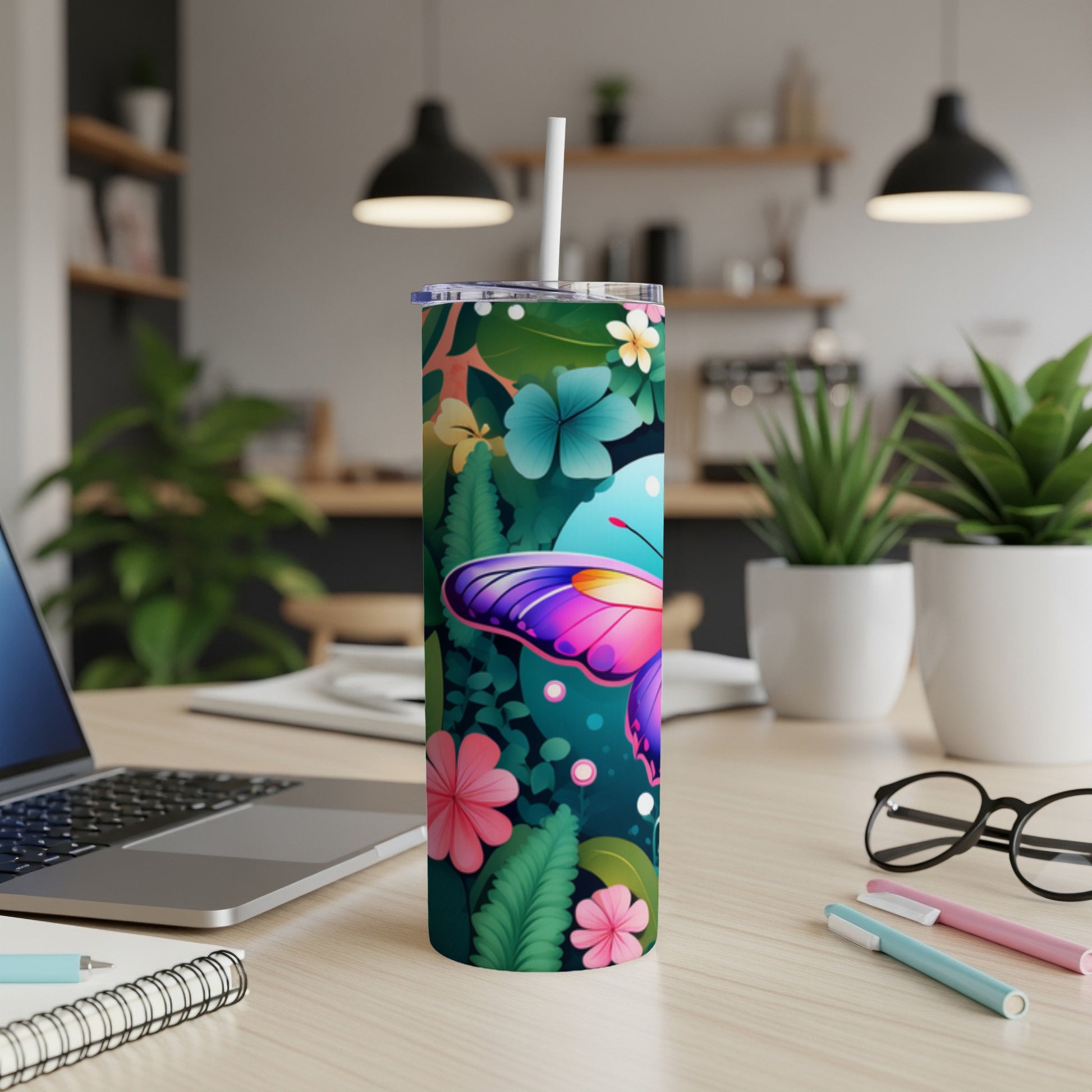 Tall tumbler with butterfly and floral pattern on a desk.