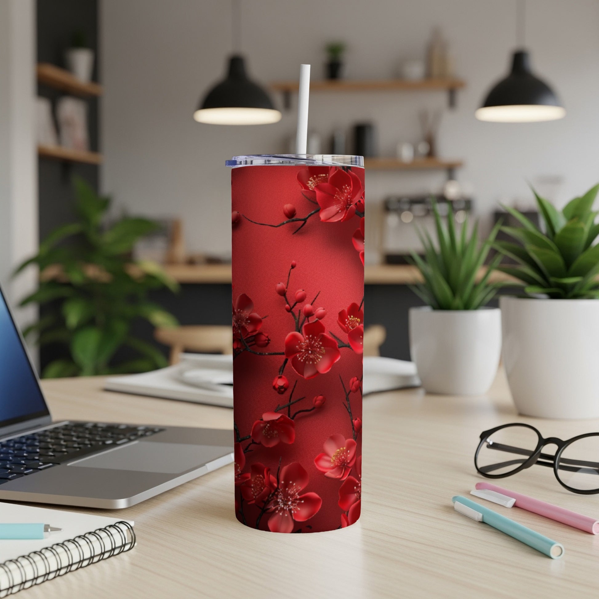 Red tumbler with dark floral cherry blossom pattern and straw.
