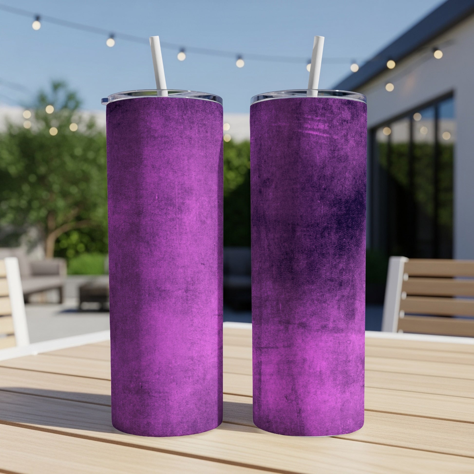 Two purple textured tumbler cups with white straws on a wooden table outdoors.