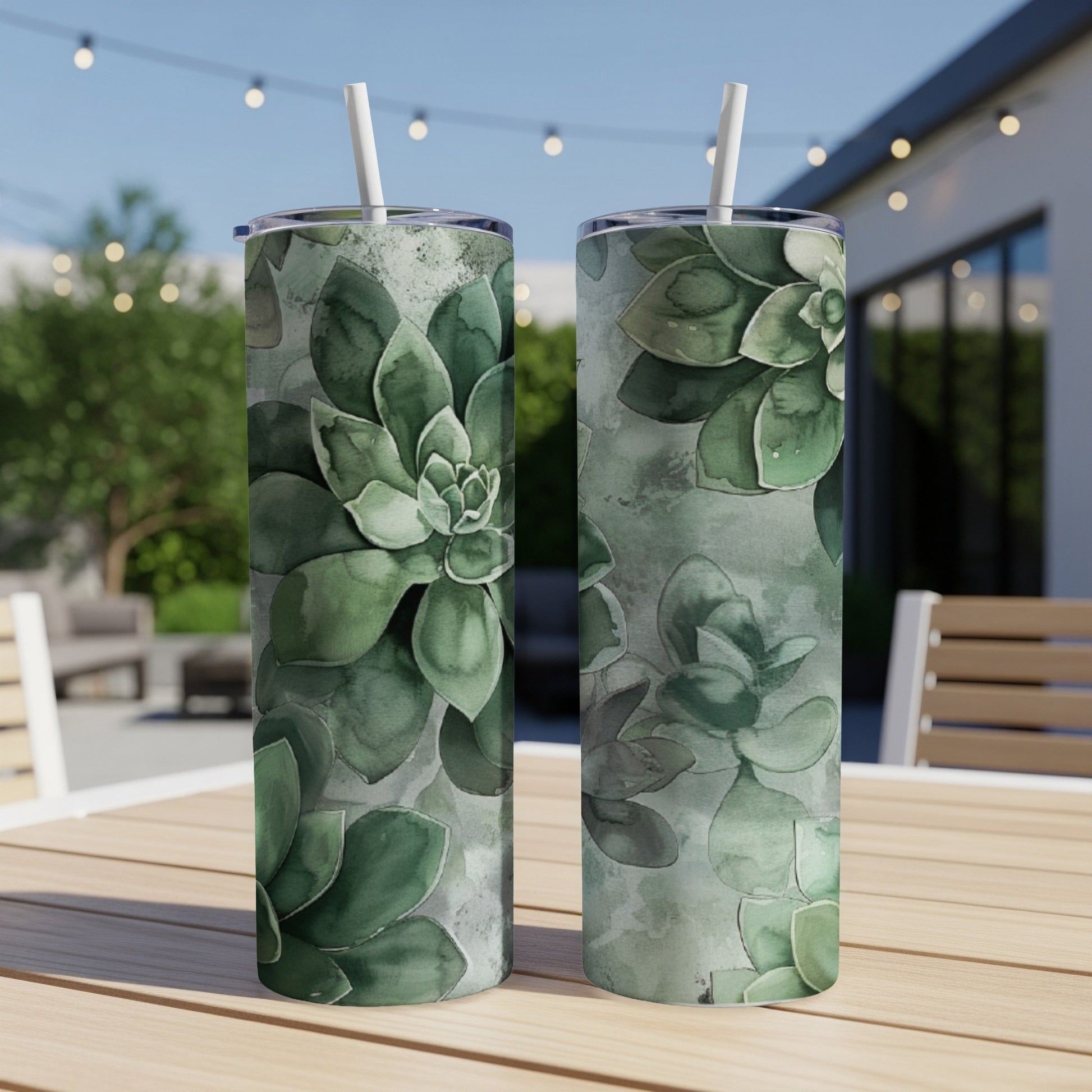 Two tall green succulent tumblers with straws on a table outdoors.