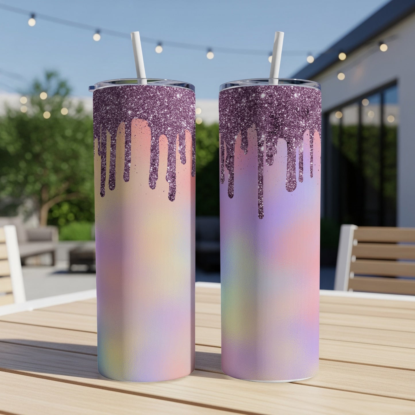 Two glitter-drip tumblers with pastel ombre designs and white straws sit on a wooden table.