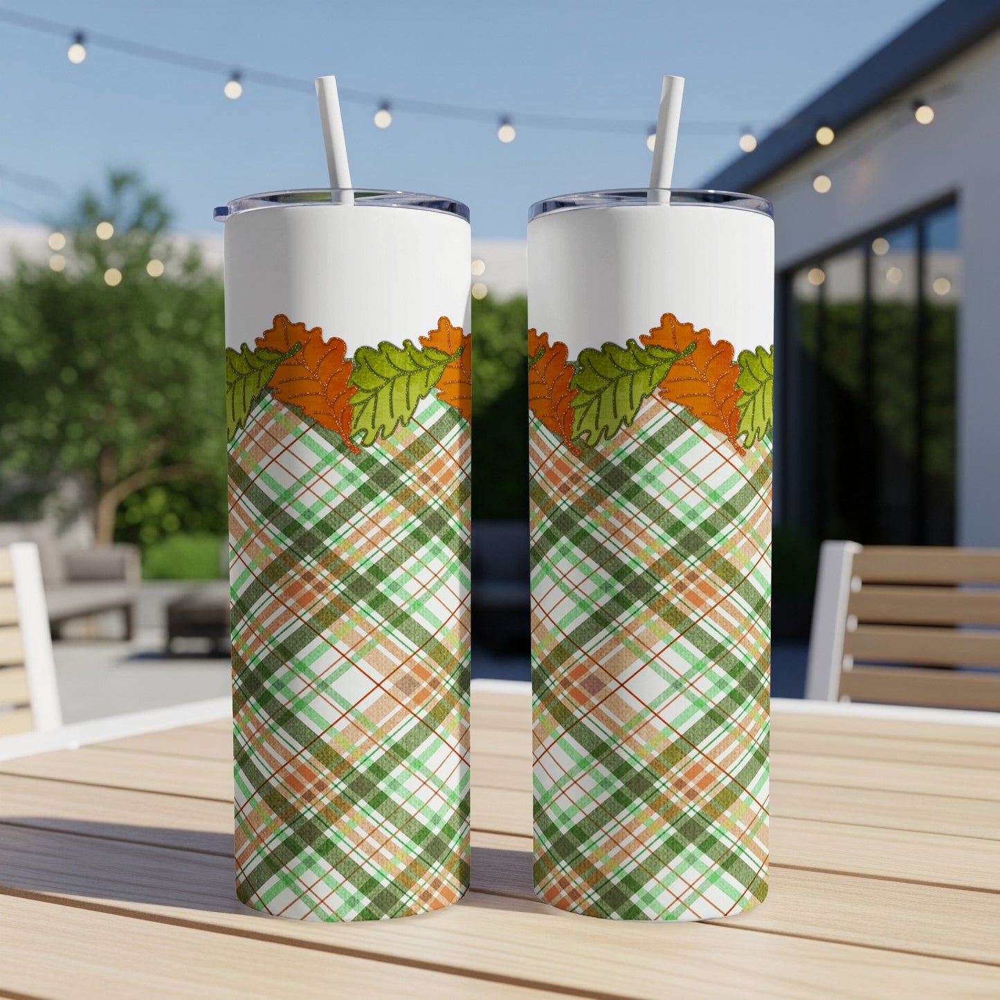 Two tumblers with plaid and leaf design on a wooden table.
