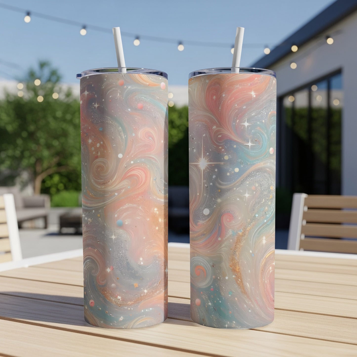 Two tumblers with pastel galaxy swirl design and straws on a wooden table.