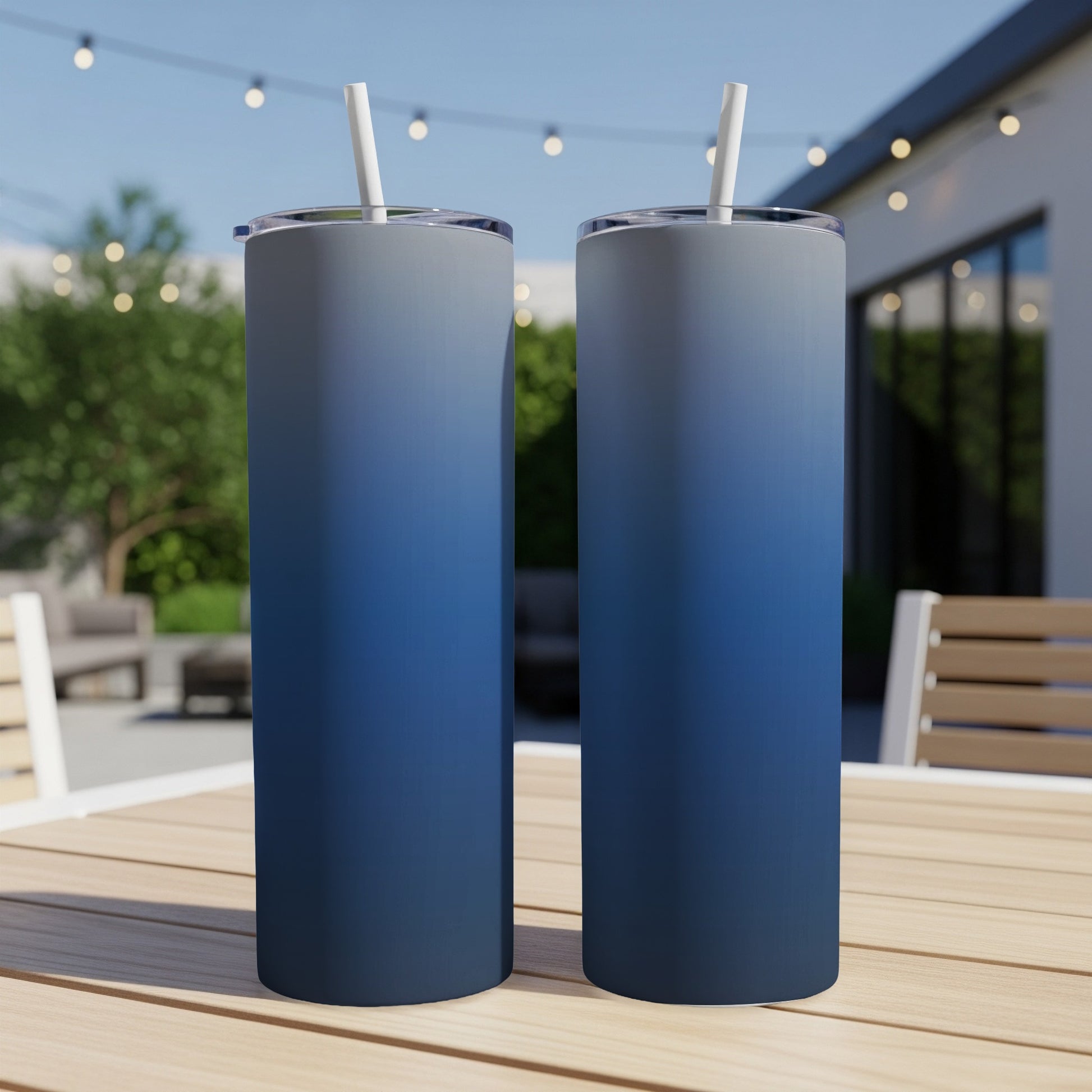 Two tall blue ombre tumblers with straws on a wooden table.