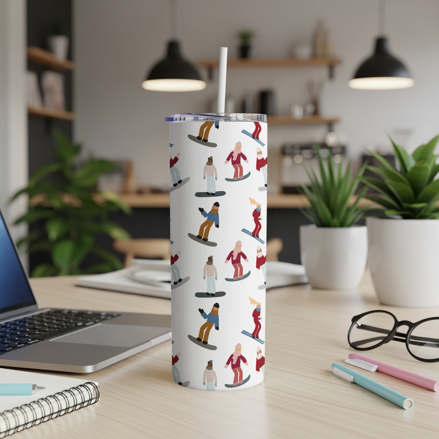 White tumbler with repeating cartoon snowboarders and a straw.