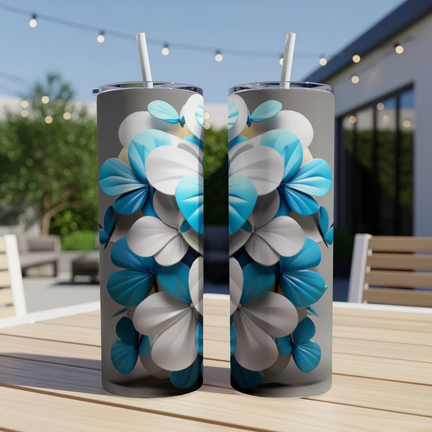 Two tumblers with blue and white floral pattern on outdoor table.