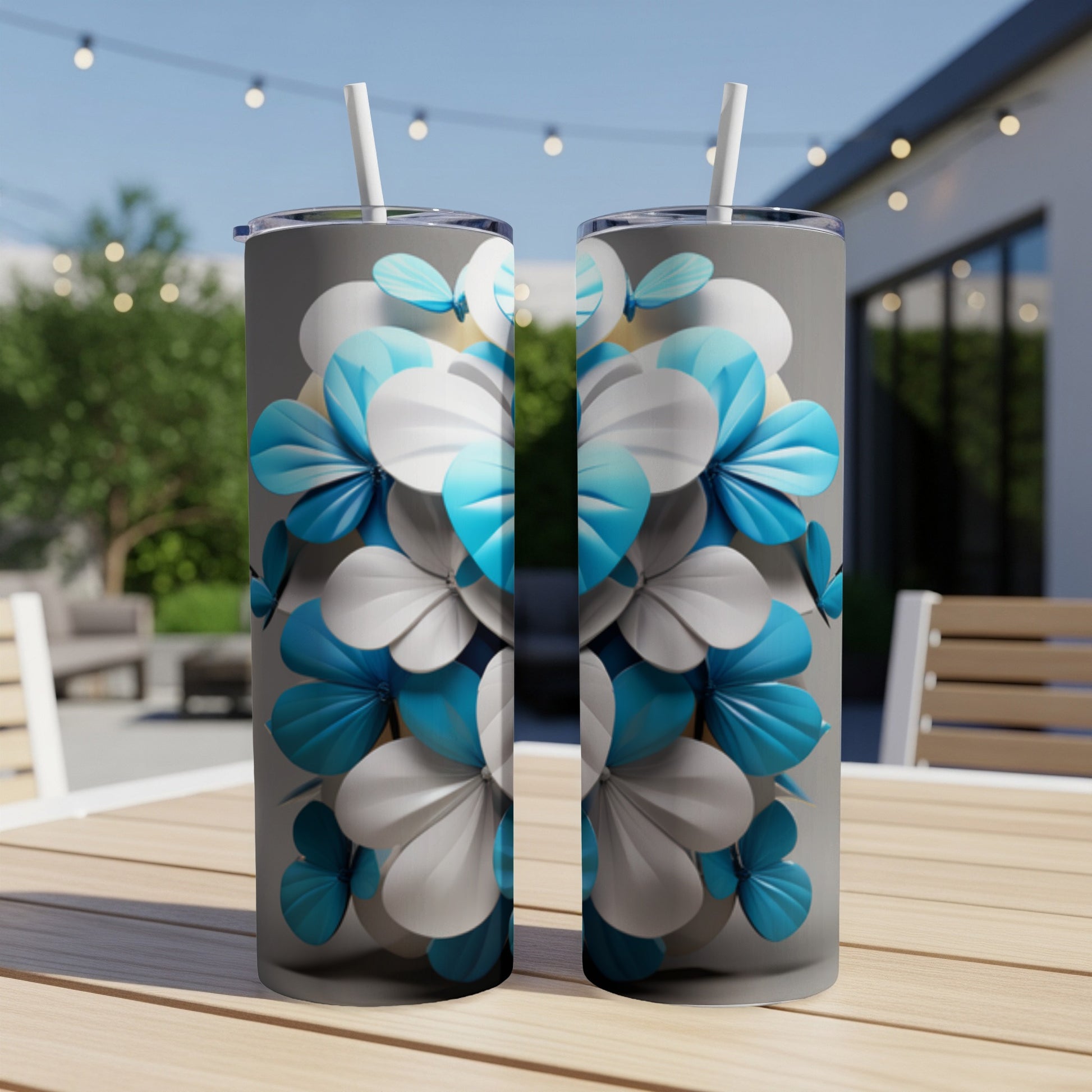 Two tumblers with blue and white floral pattern on outdoor table.