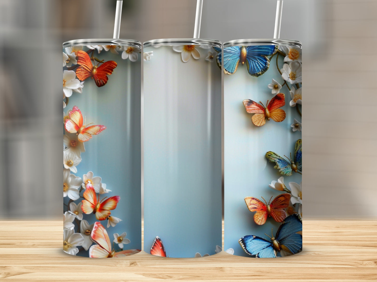 Three tumblers with butterflies and flowers on a wooden surface.