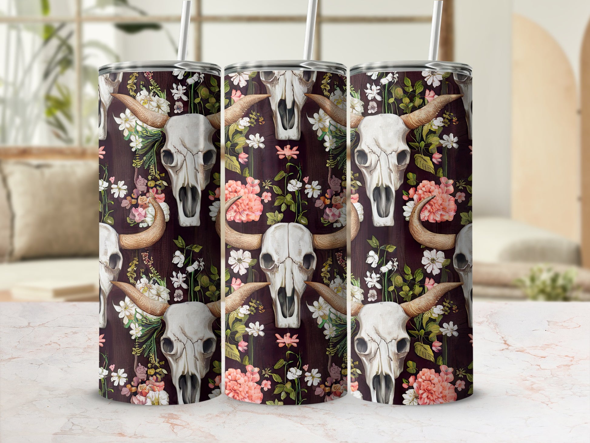 Floral skull pattern on three tumblers with straws, on a marble surface.