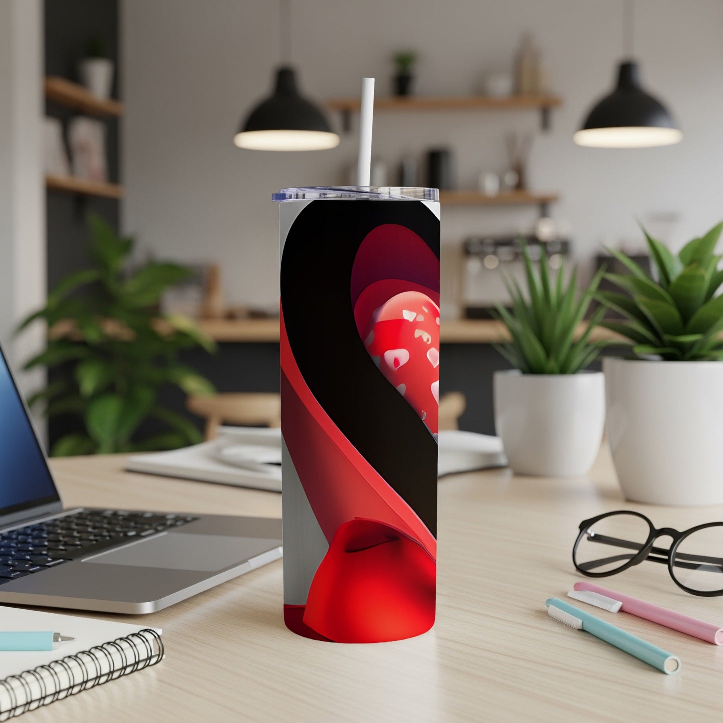 Tall tumbler with red hearts design and straw on a desk.