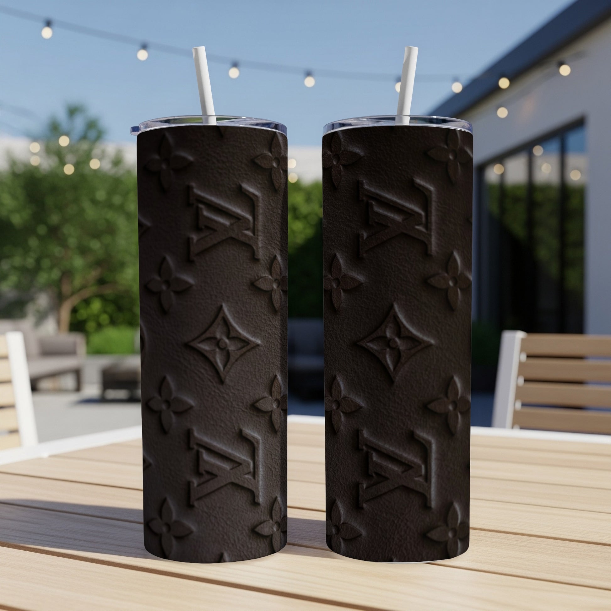Two dark brown tumblers with repeating LV monogram pattern, on a table outdoors.