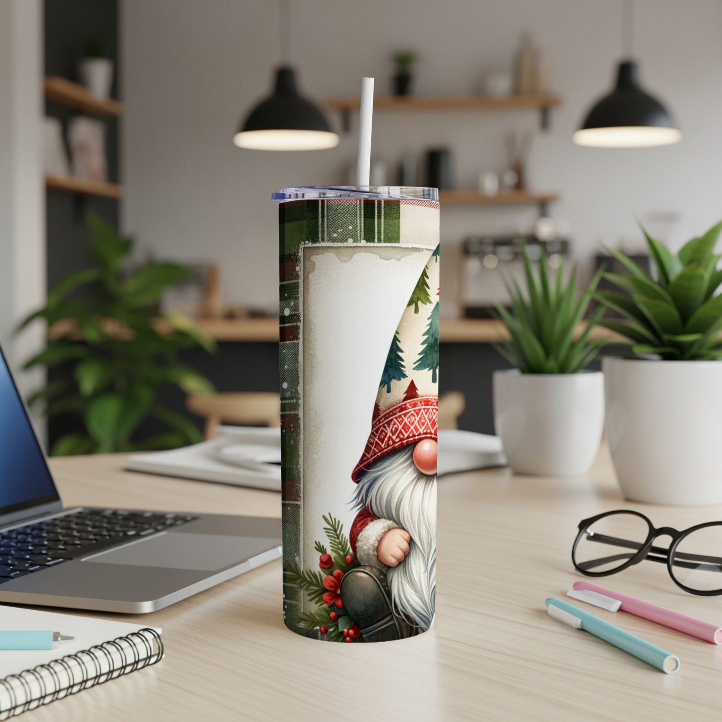 Christmas gnome tumbler with trees and red plaid accents on a desk.