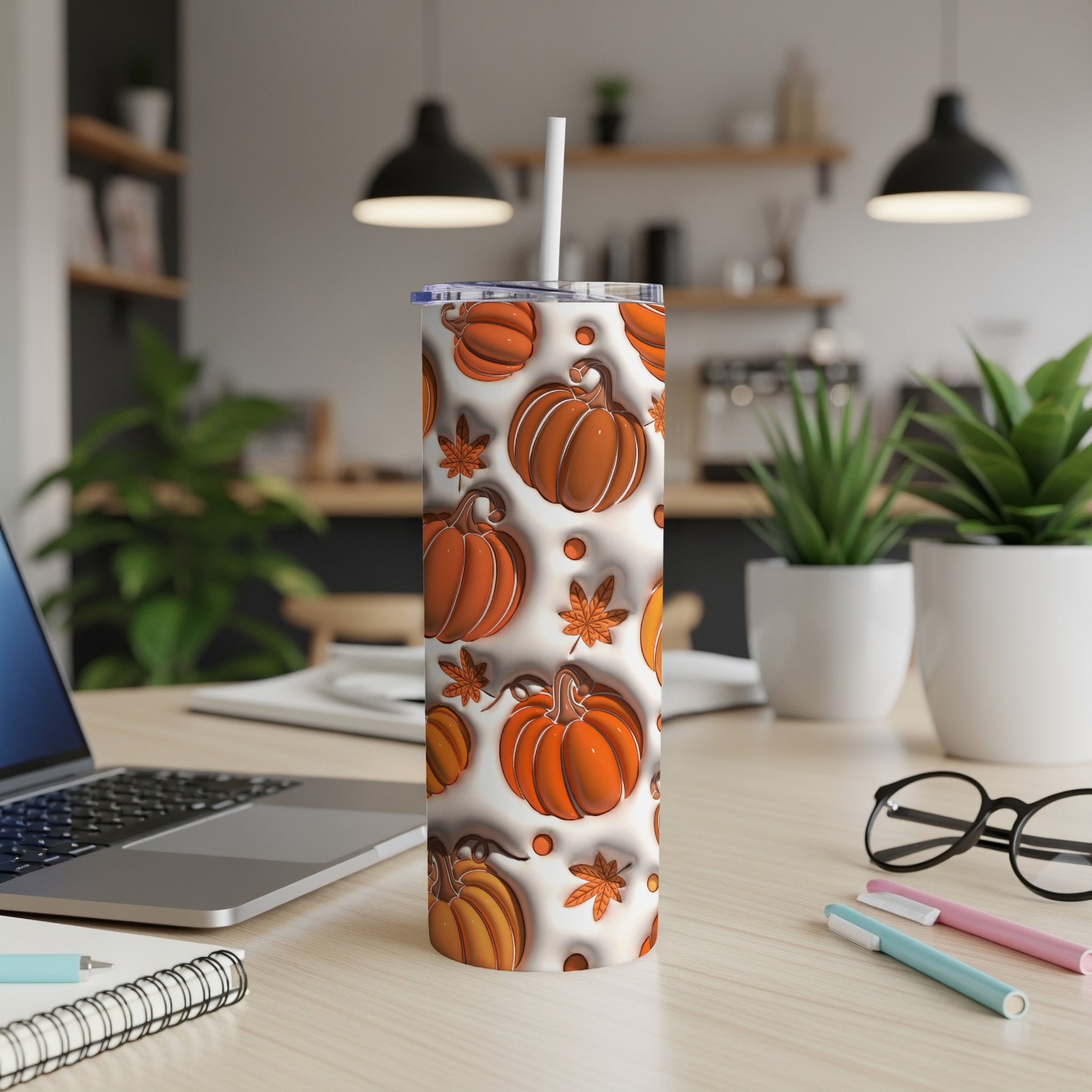 White tumbler with pumpkin and leaf pattern, on desk with laptop.
