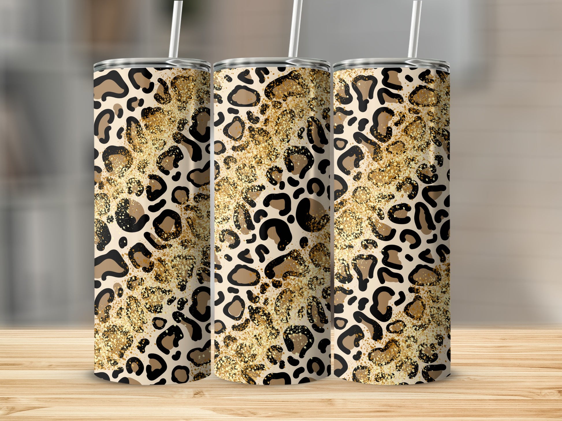Three tumblers with leopard print and gold glitter on a wooden surface.