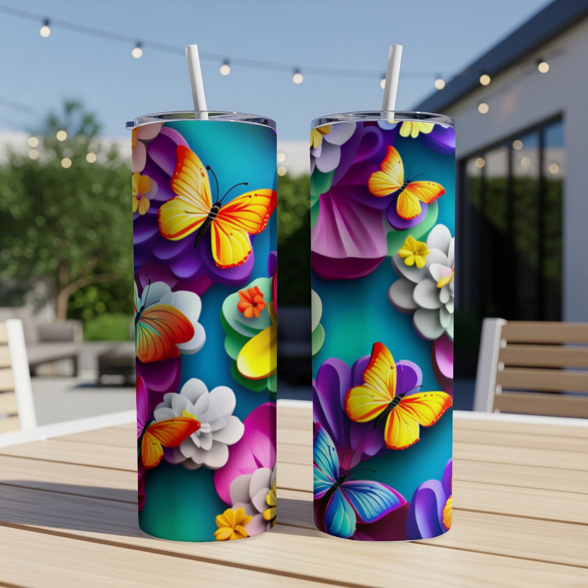Two tumblers with vibrant floral and butterfly patterns displayed outdoors.