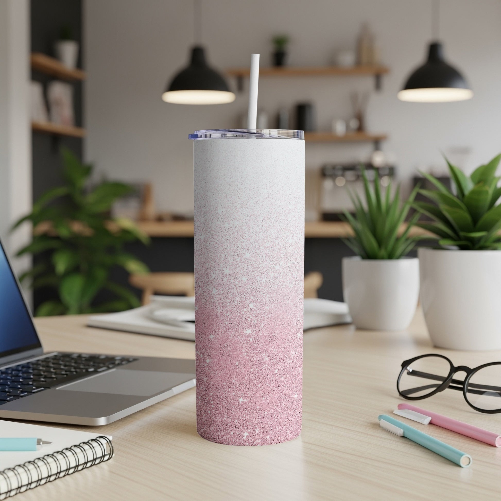 White and pink glitter gradient tumbler with straw on desk.