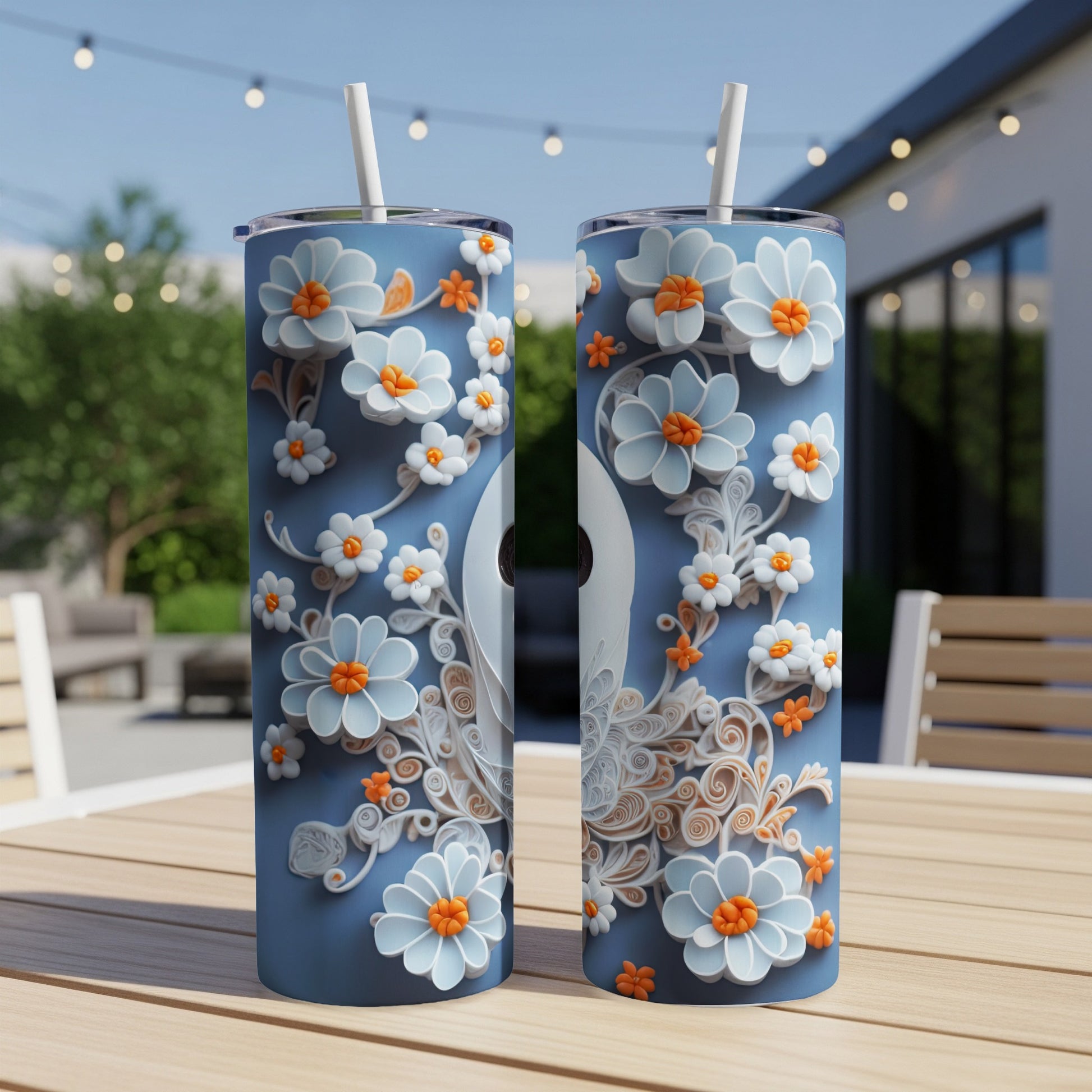 Two blue tumblers with light blue and orange floral designs and white straws.
