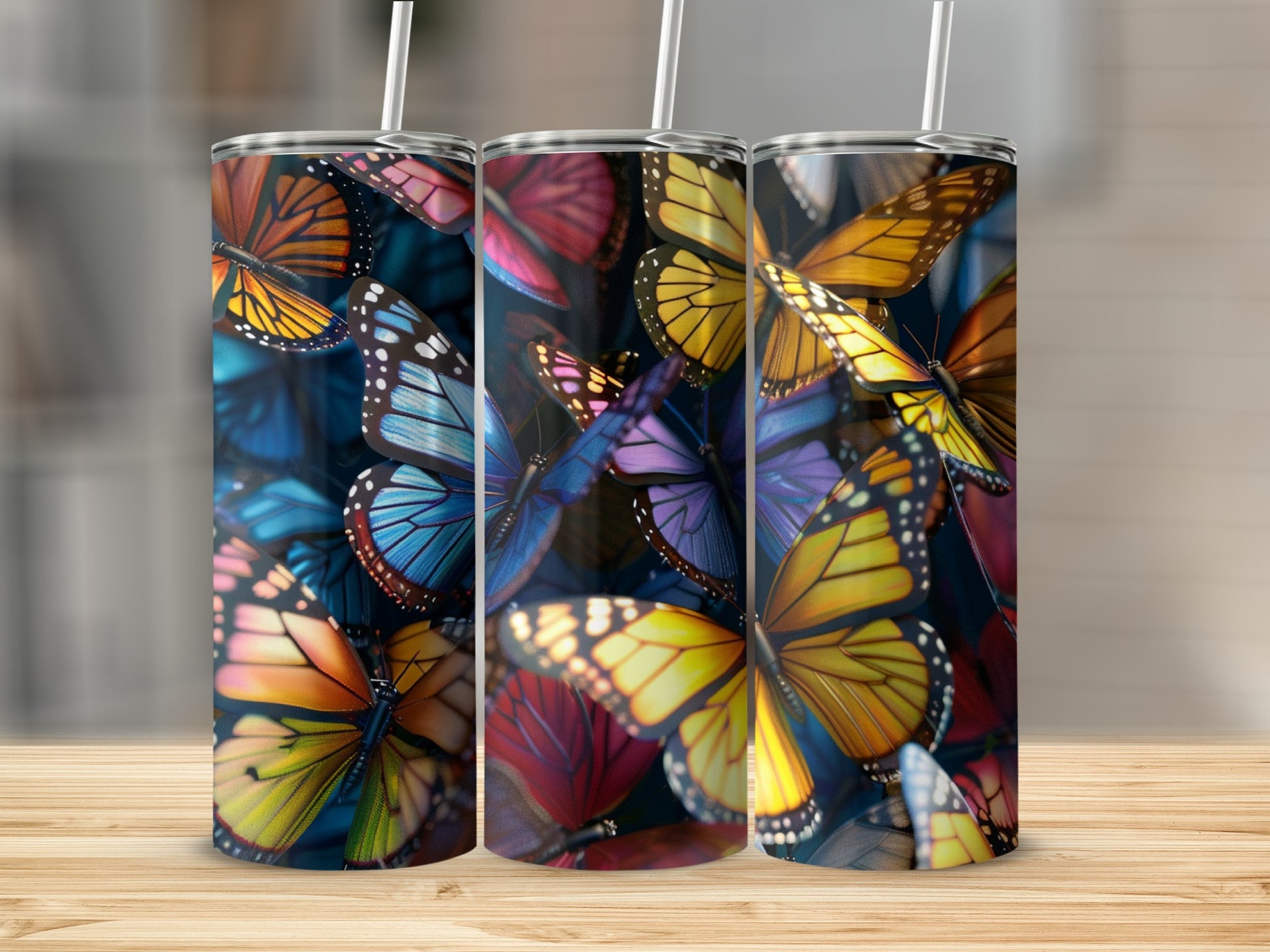 Three tumblers with colorful butterfly designs, shown on a wooden surface.