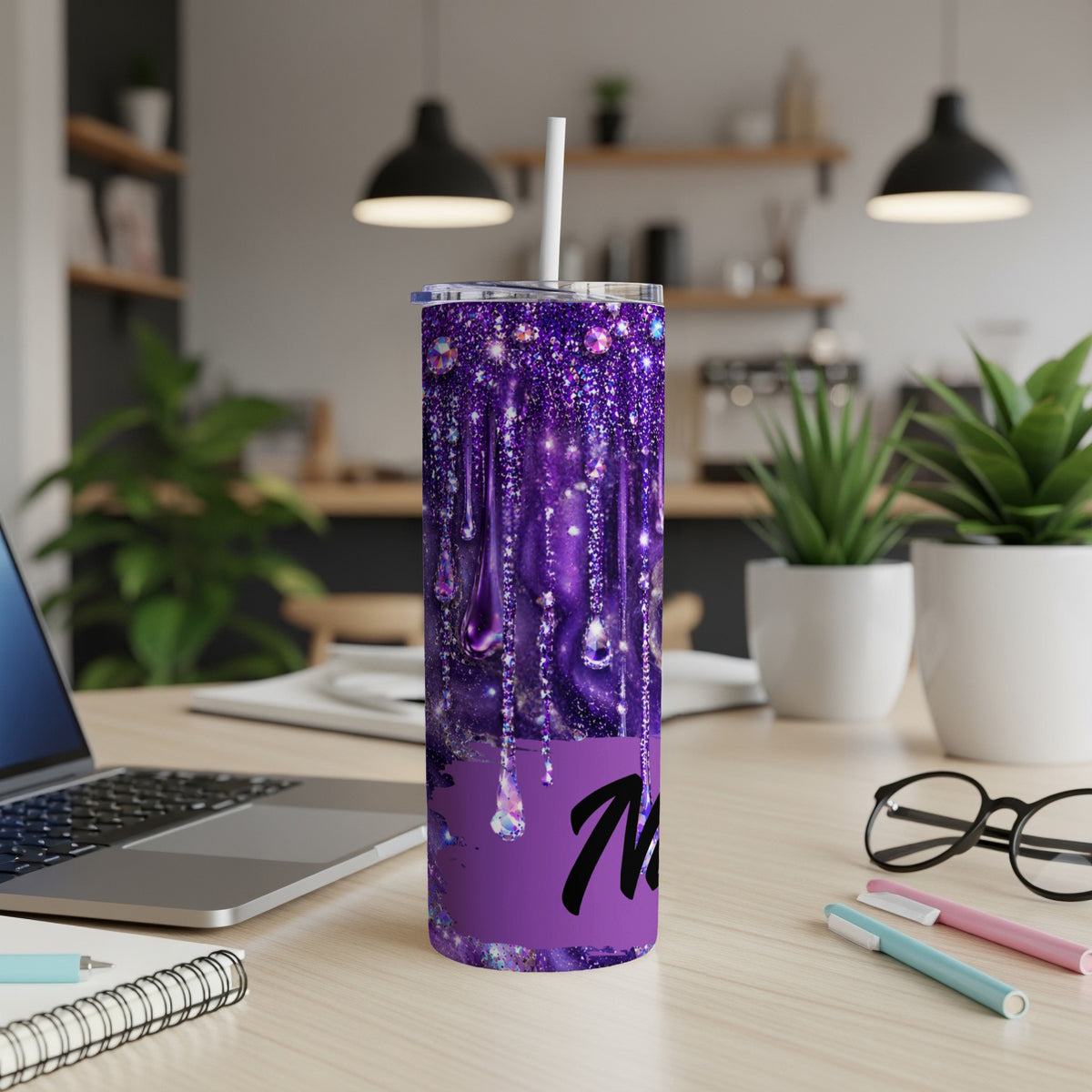 Purple glitter drip tumbler with "M" initial on a desk.