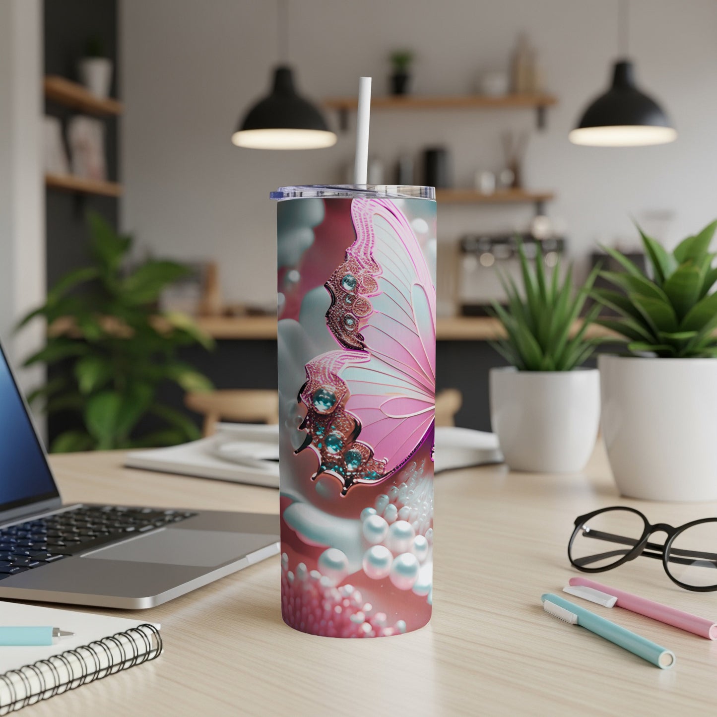 Pink butterfly tumbler with pearls and jewels on a desk.