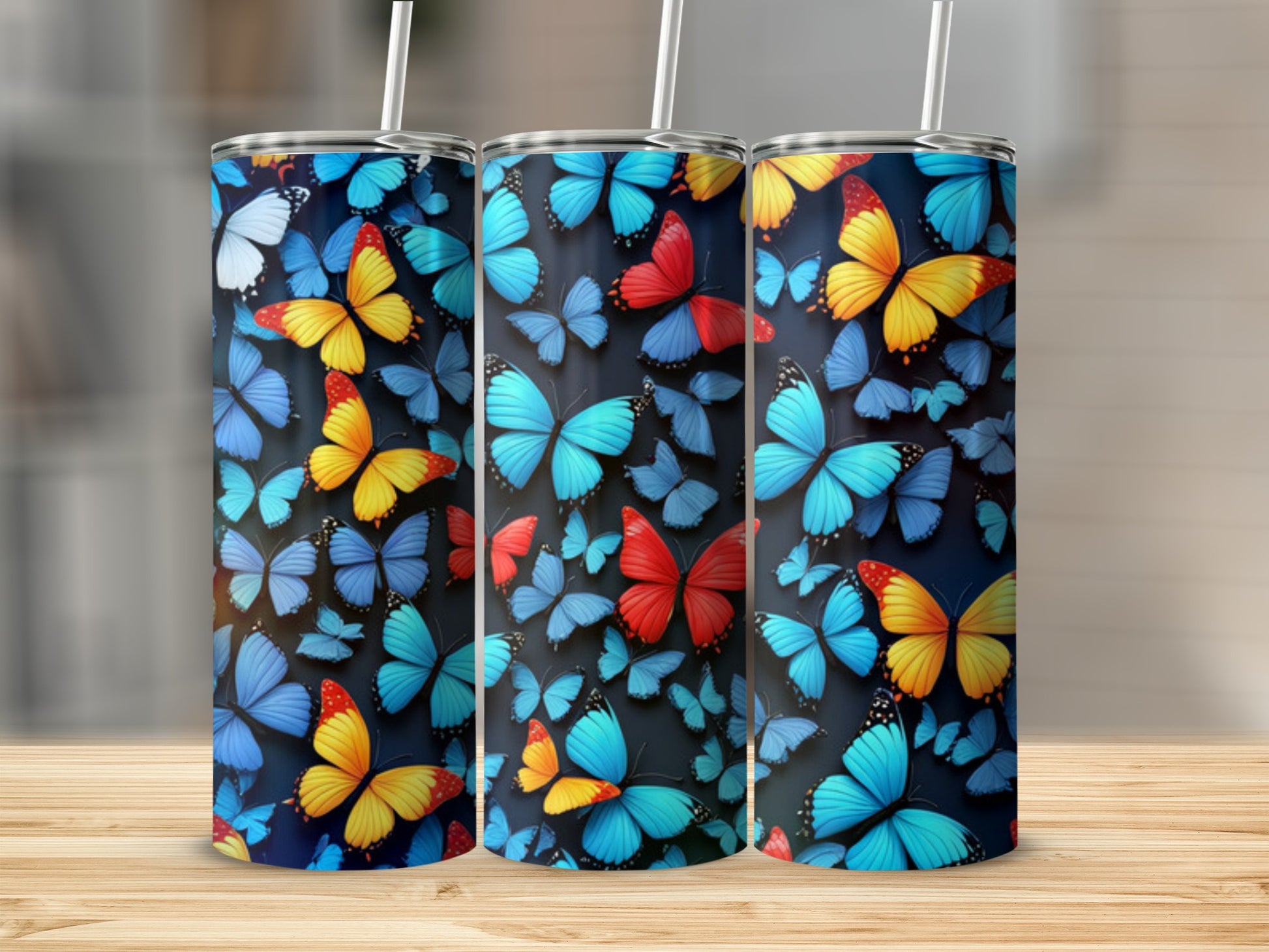 Three tumblers adorned with colorful butterfly patterns on a wooden surface.