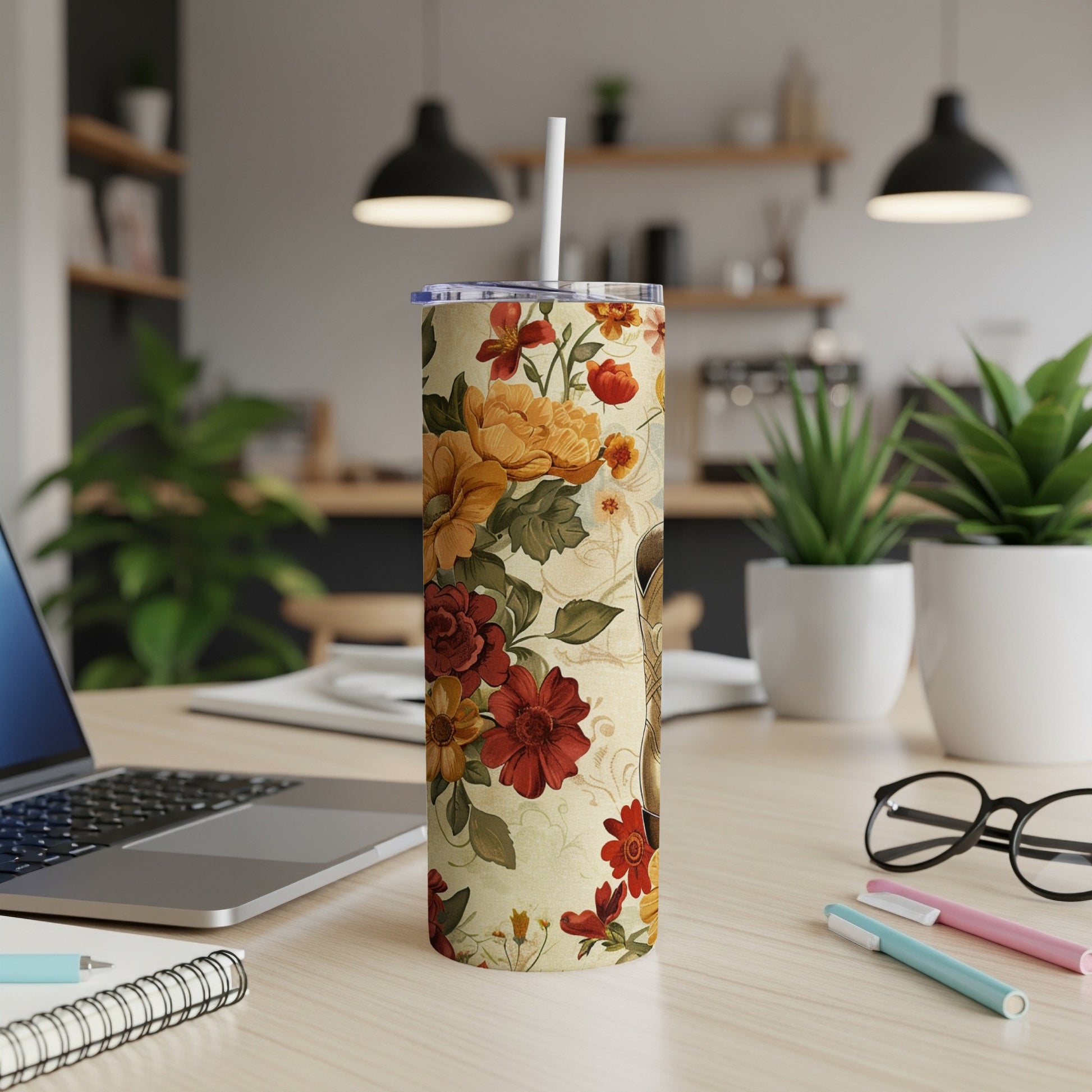 Floral patterned tumbler with a straw on a desk.