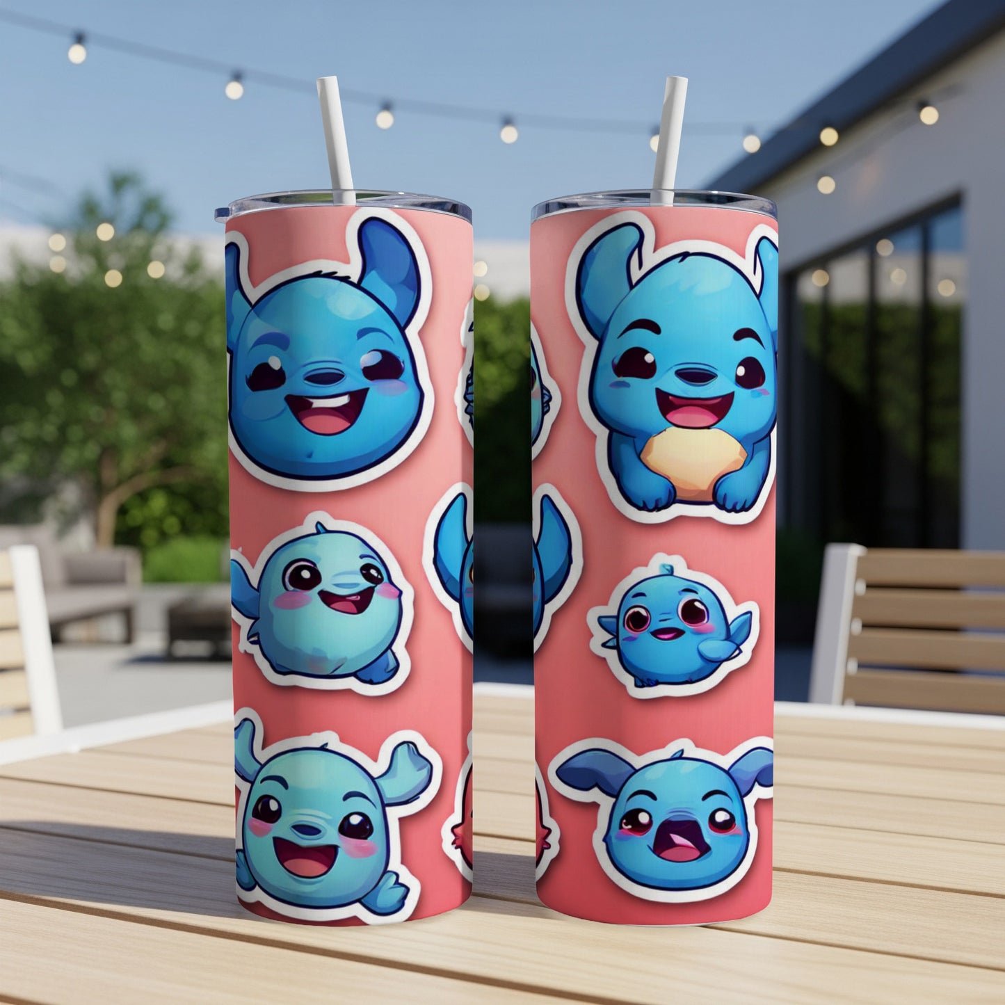 Two pink tumblers with blue cartoon creature stickers on a wooden table.