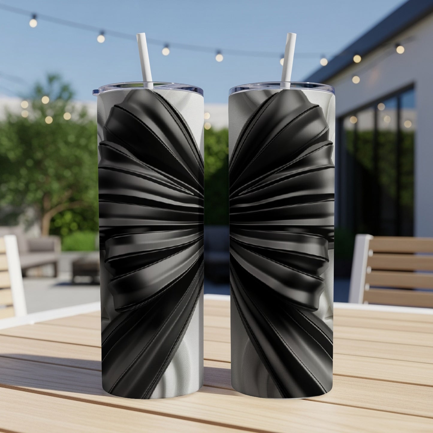 Two tumblers with black ribbon design on a wooden table outdoors.