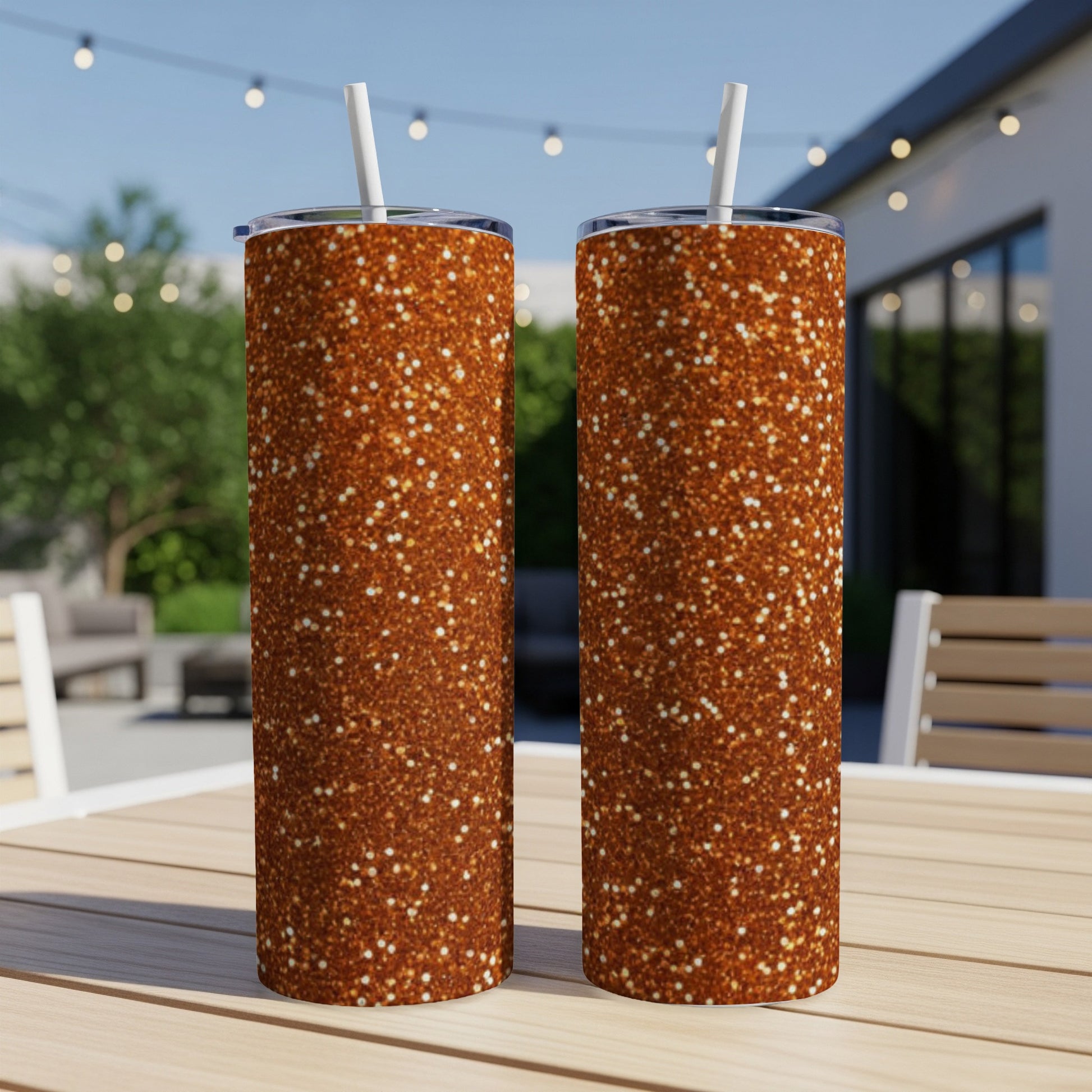 Two tall tumblers with a sparkly copper glitter design on a wooden table.