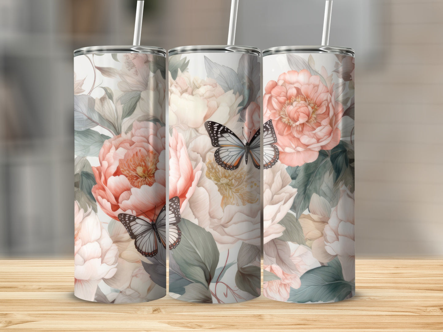 Three tumblers with floral and butterfly designs on a wooden surface.