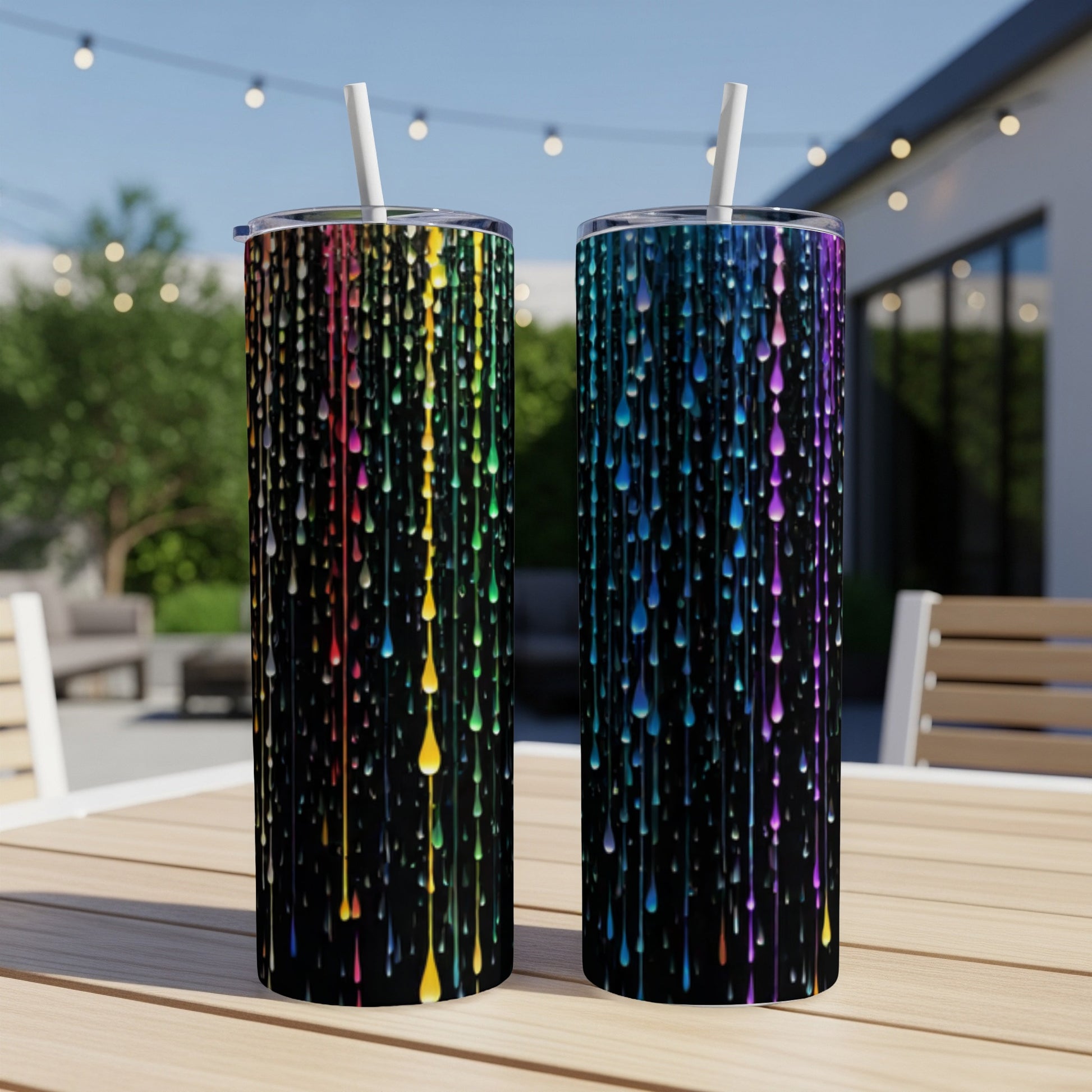 Two black tumblers with colorful dripping paint design and straws.