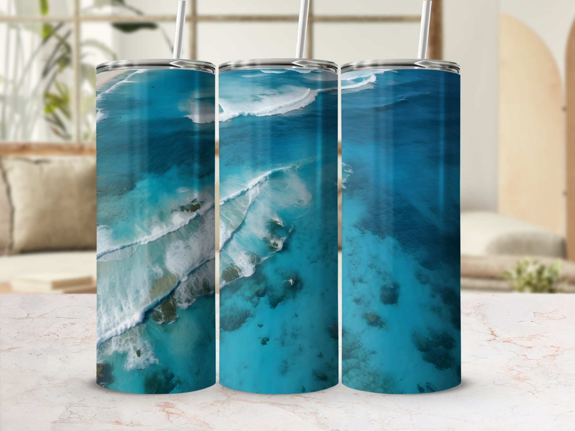 Three tumblers with aerial ocean wave design on marbled surface.