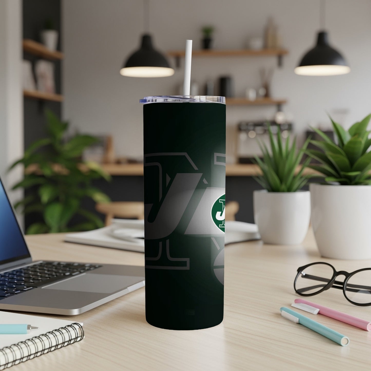 New York Jets tumbler with straw on wooden desk.