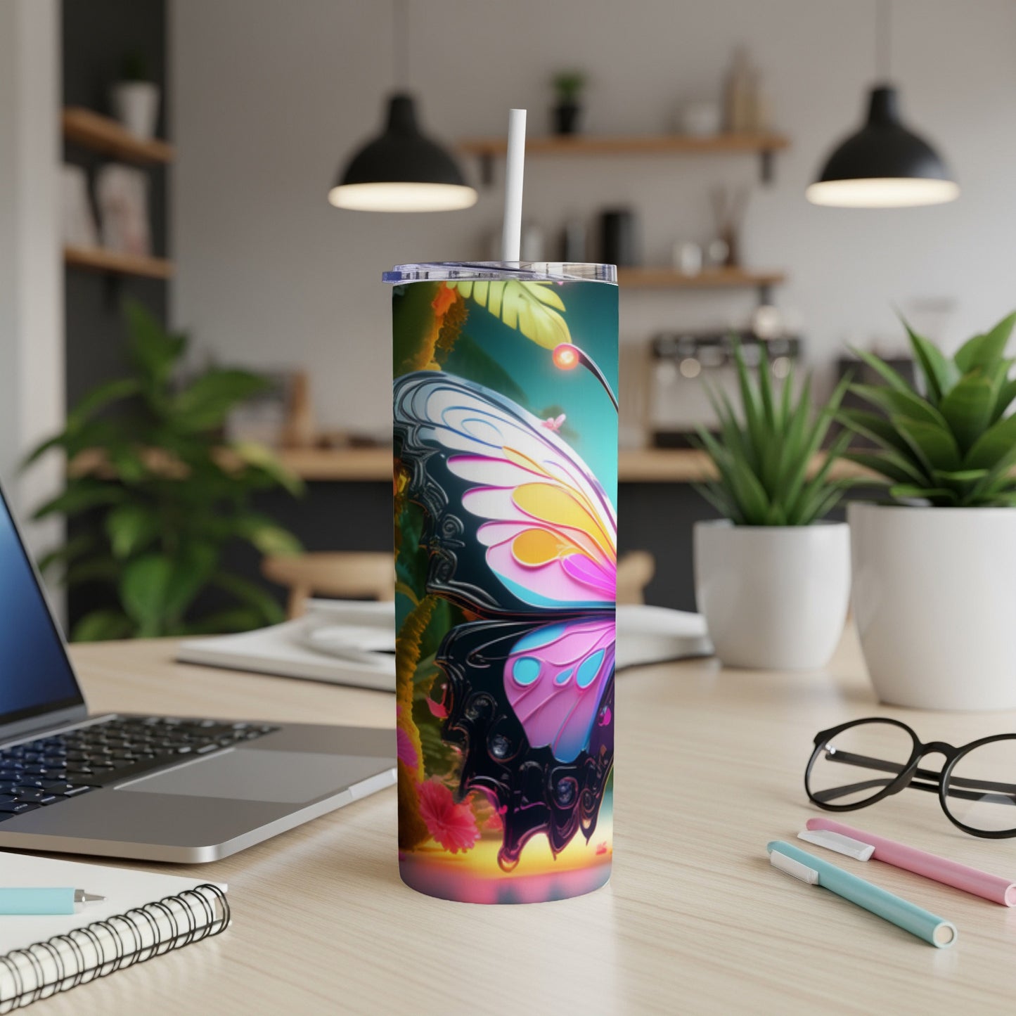 Butterfly design tumbler with straw on a desk.