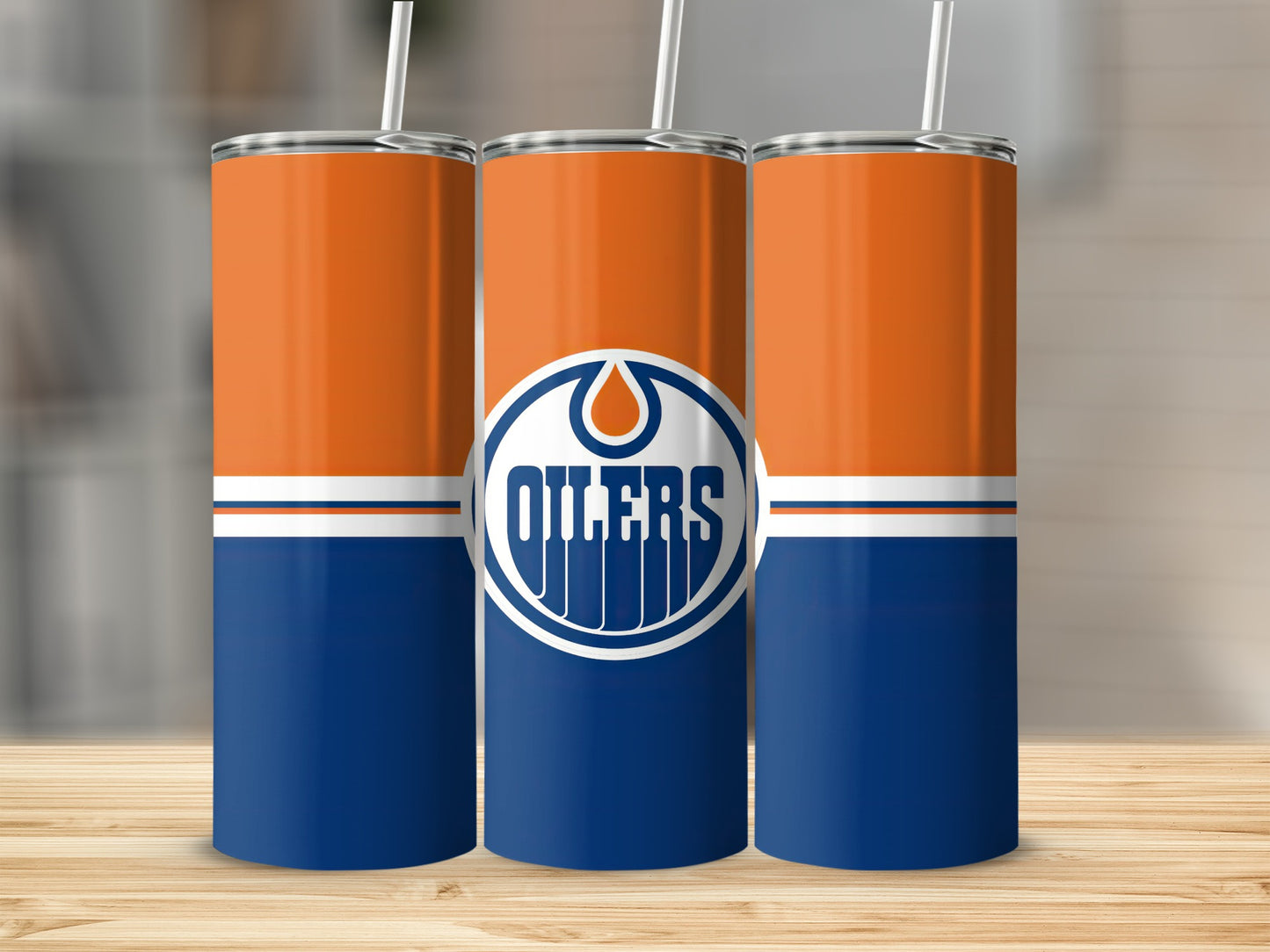 Three Oilers-themed tumblers with orange and blue design and white straws.