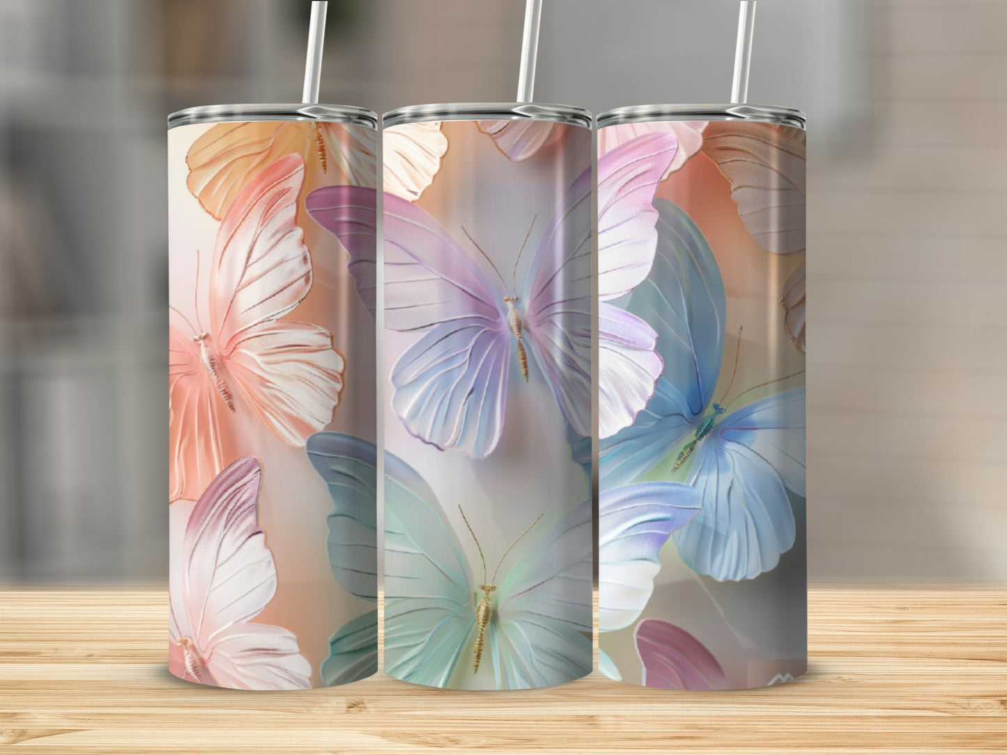 Three tumblers with pastel butterfly designs on a wooden surface.