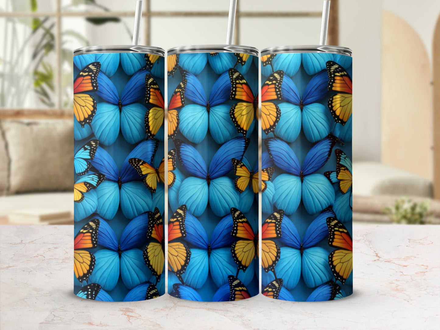 Three tumblers with a vibrant blue butterfly pattern on a marble surface.