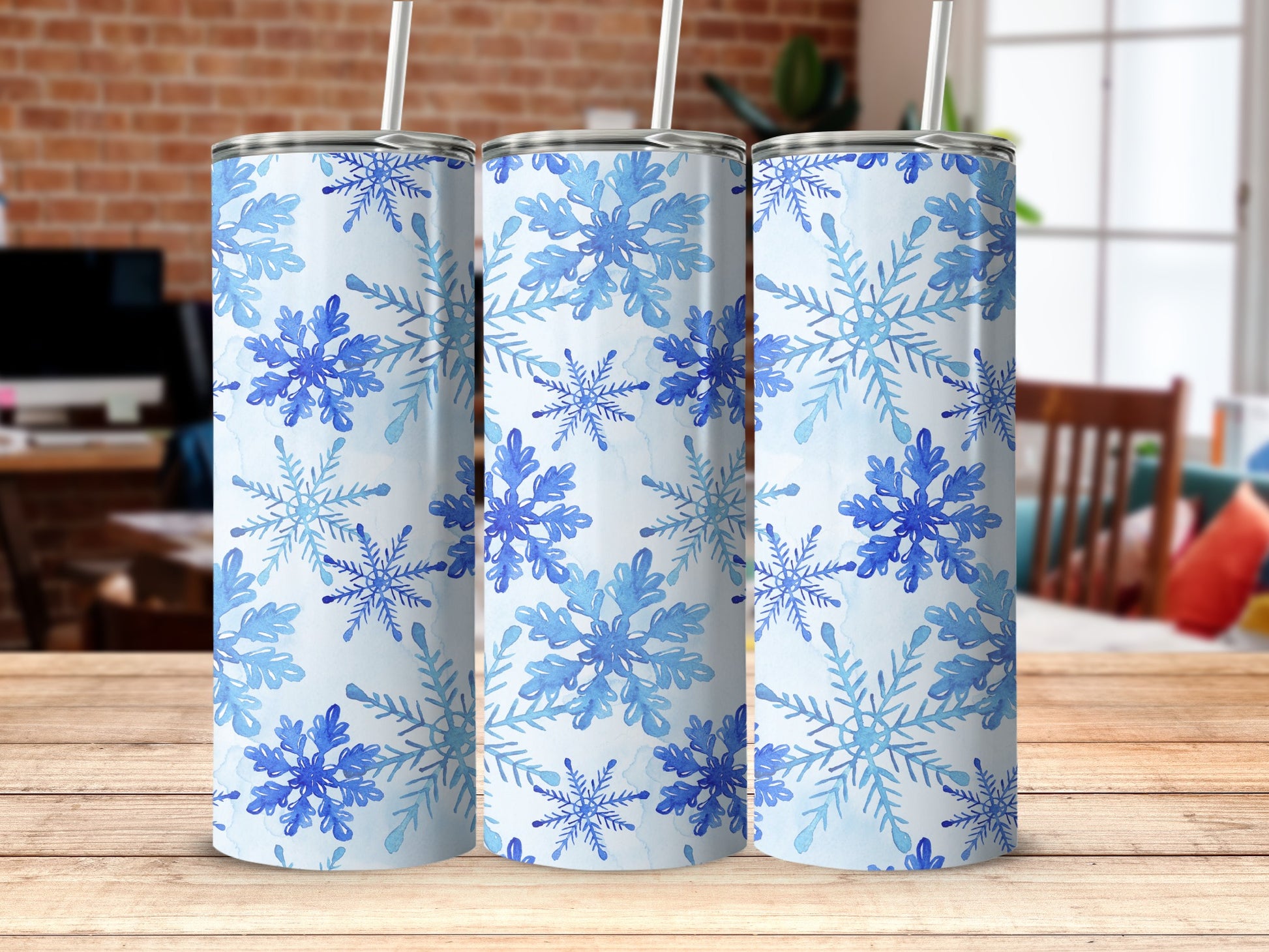 Three tumblers with a blue snowflake pattern on a wooden surface.