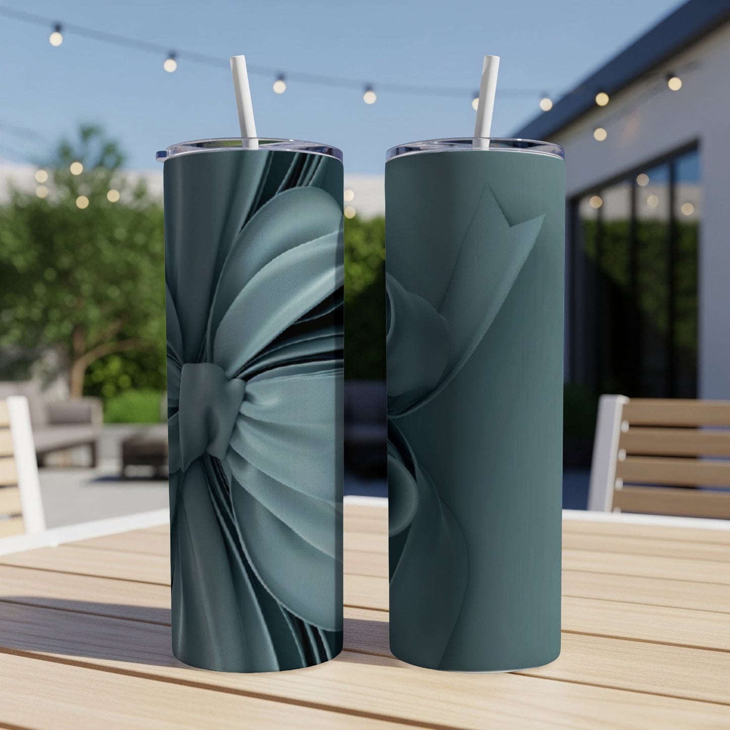 Two teal tumblers with a stylized ribbon design on a wooden table.