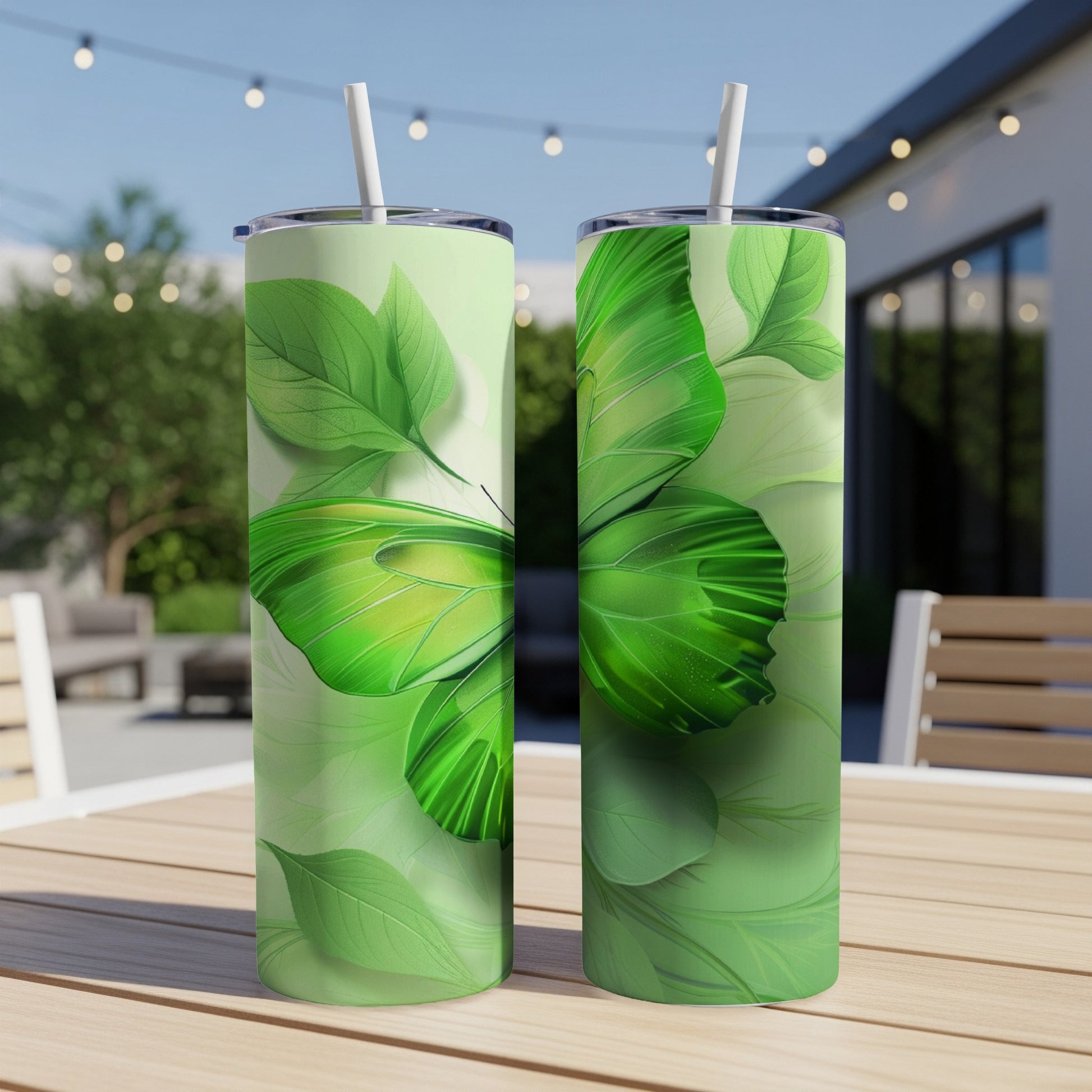 Two green butterfly tumblers with straws on a table.
