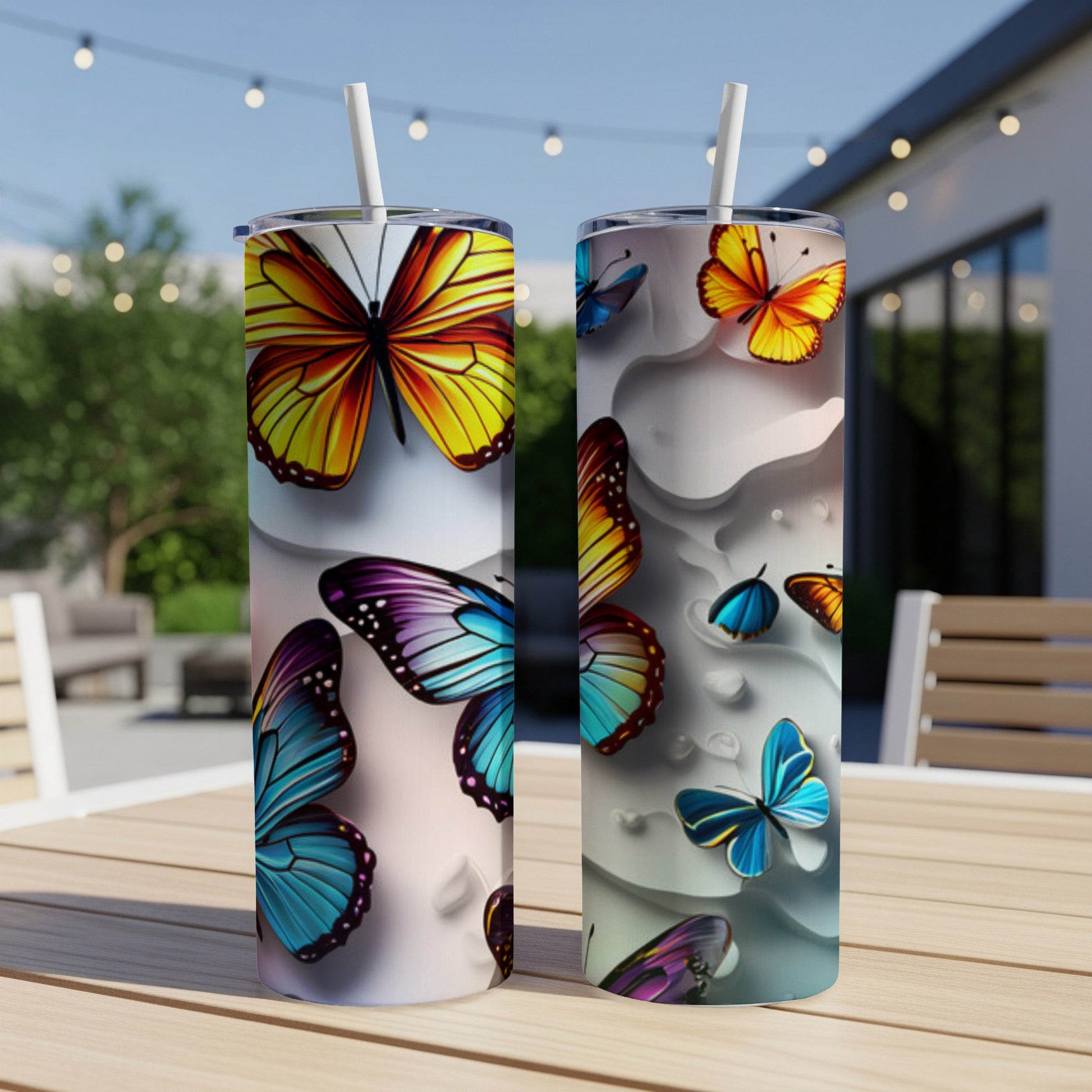 Two tumblers with colorful butterfly designs sitting on a table.