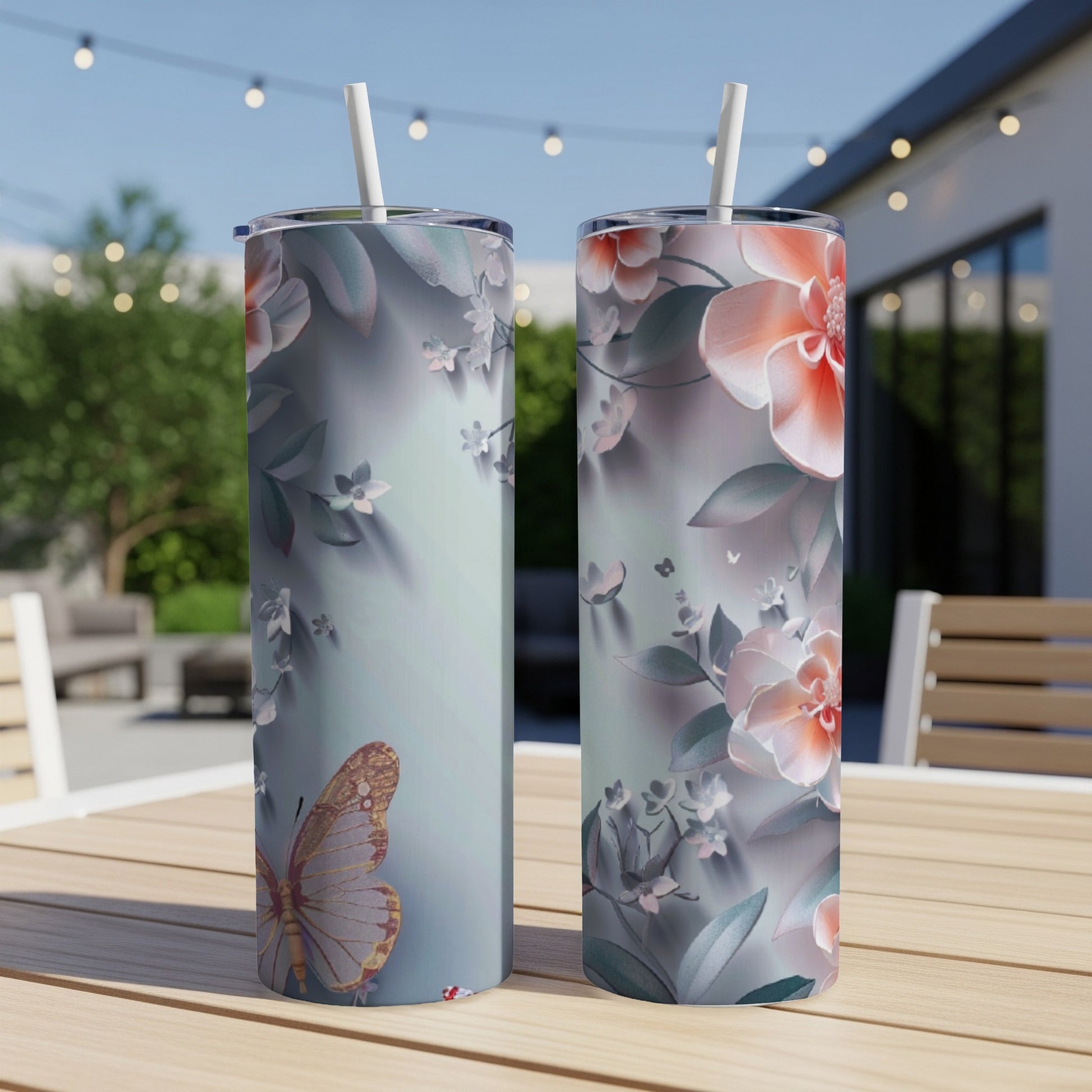 Two tumblers with a floral and butterfly design, on a table.