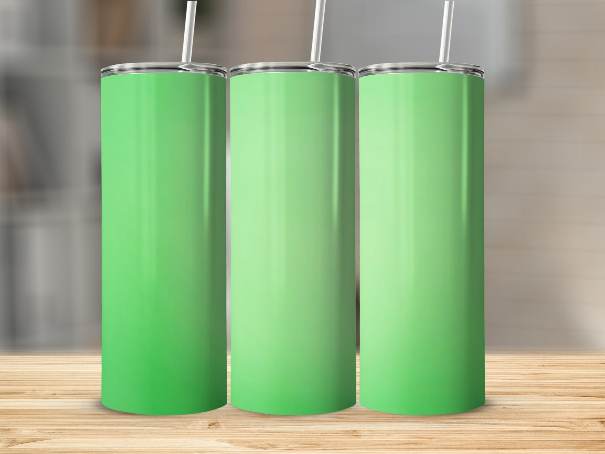 Three plain green tumblers with straws stand on a wooden surface.