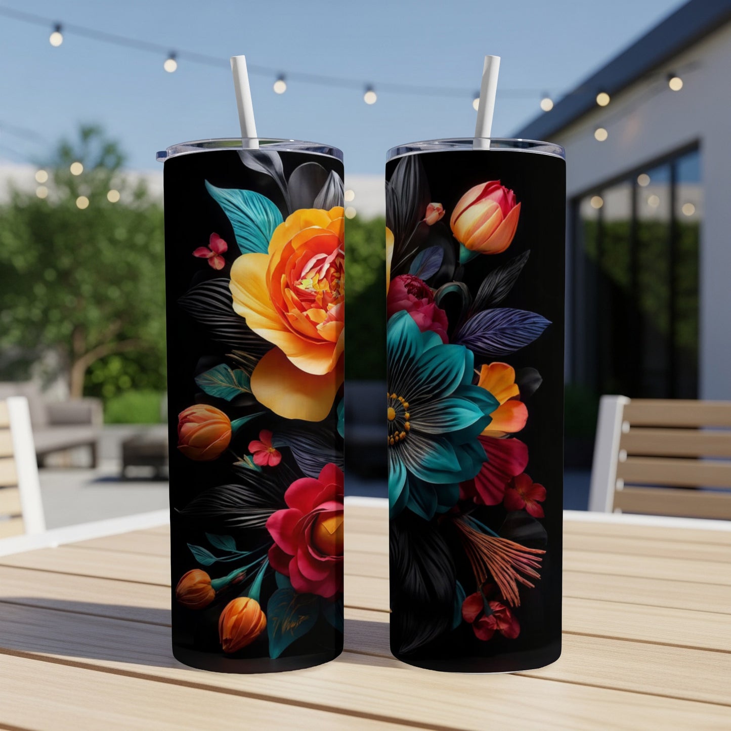 Two tall, black tumblers adorned with vibrant floral designs on a patio table.