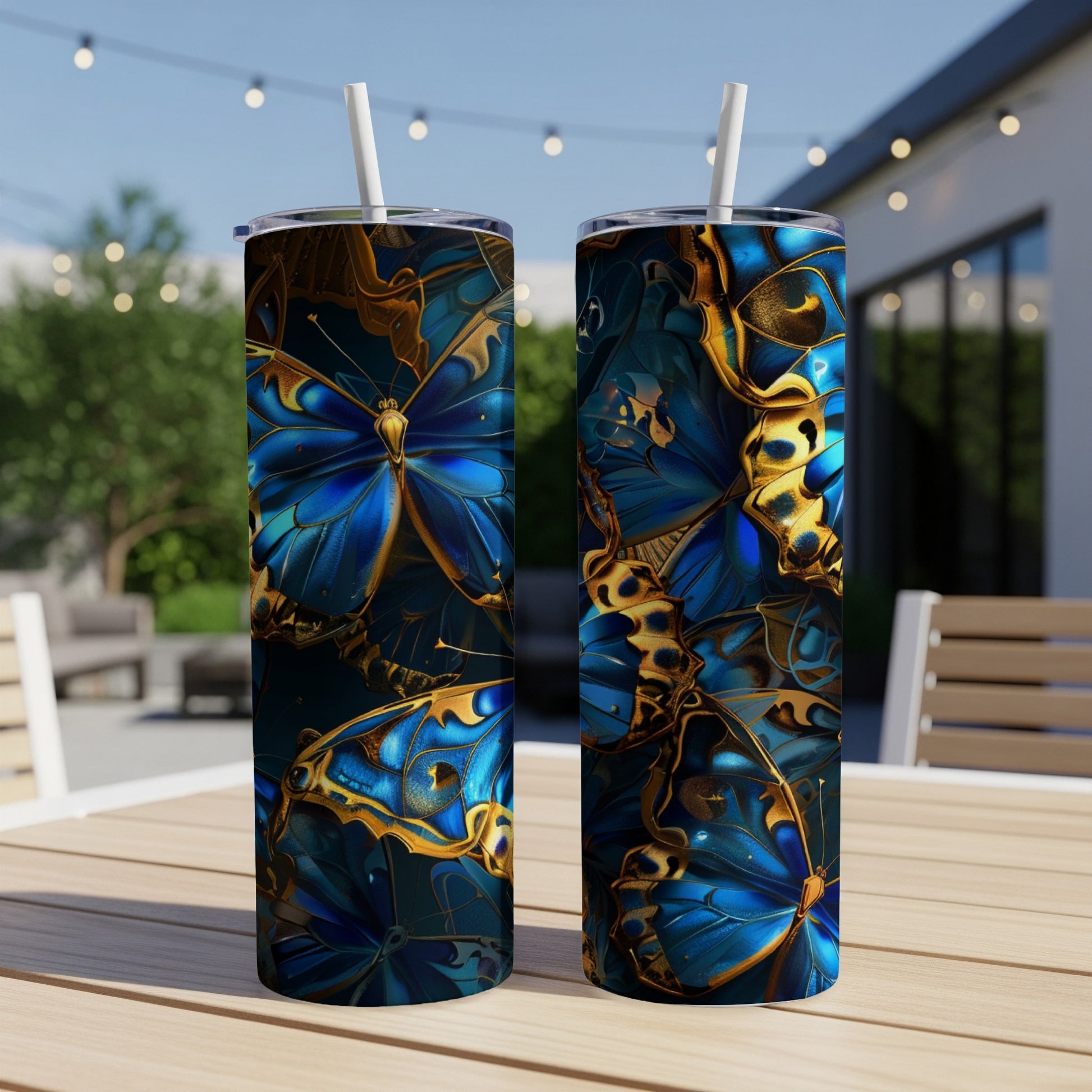 Two tumblers with a blue and gold butterfly pattern on a patio table.