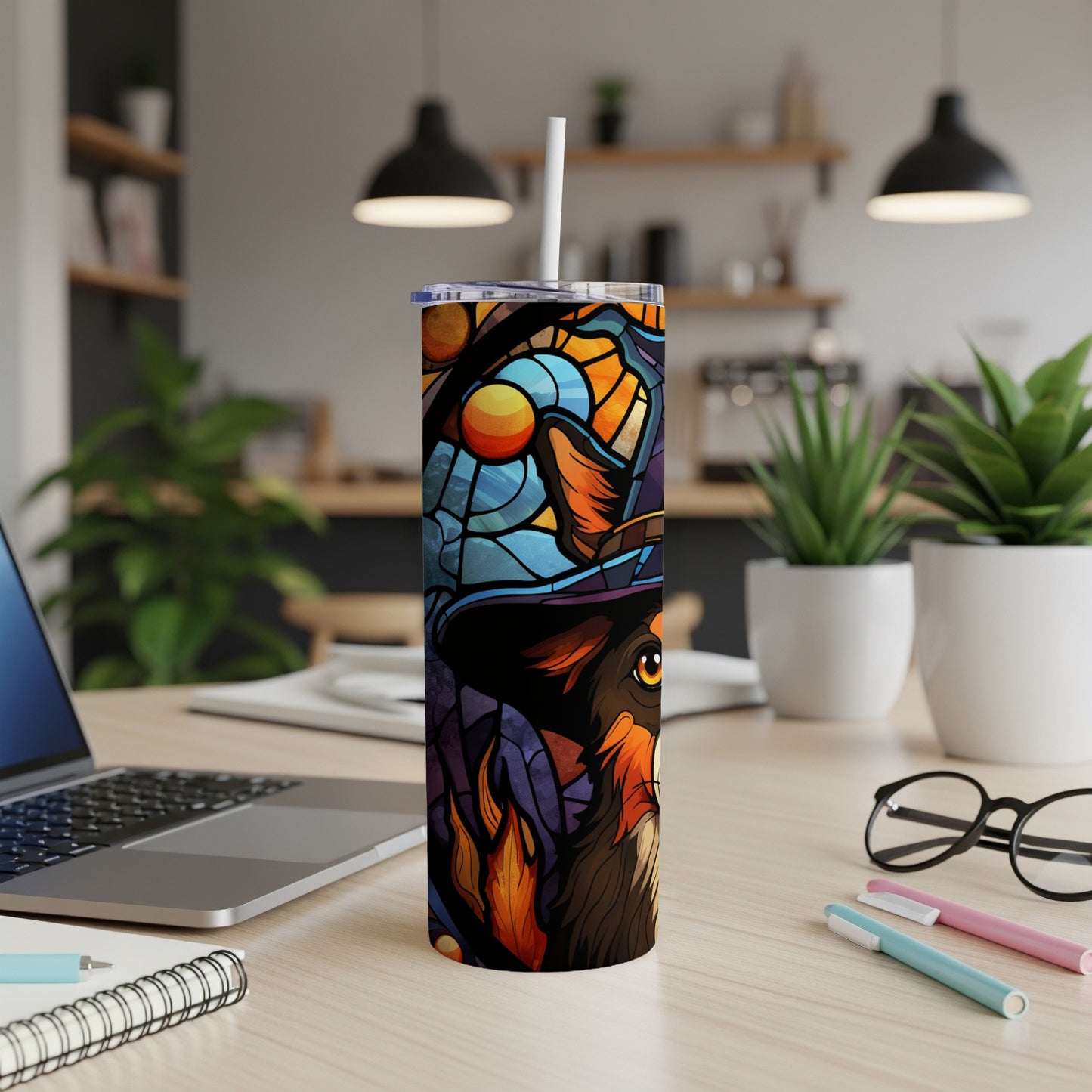 Colorful stained glass dog tumbler with hat and scarf on desk.