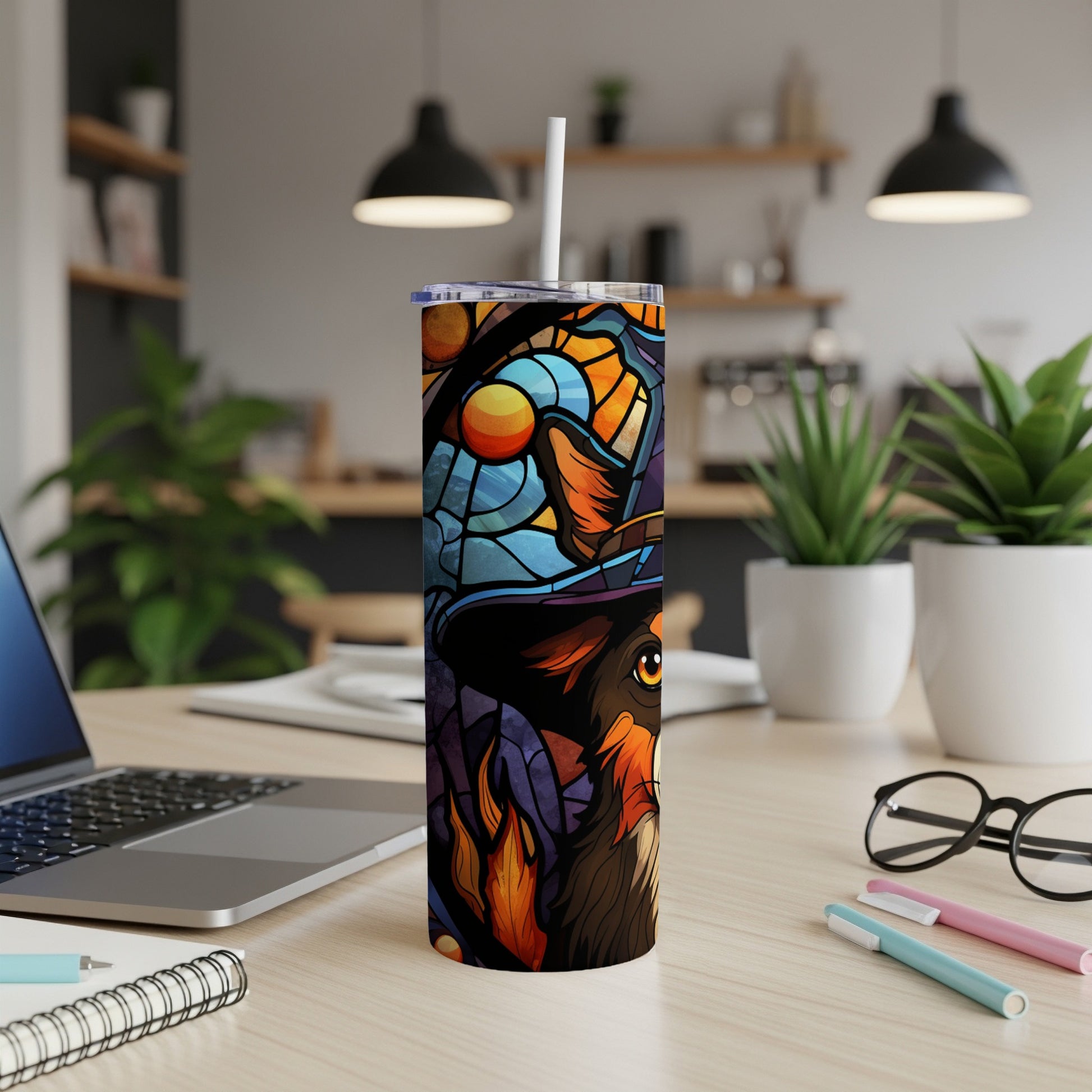 Colorful stained glass dog tumbler with hat and scarf on desk.
