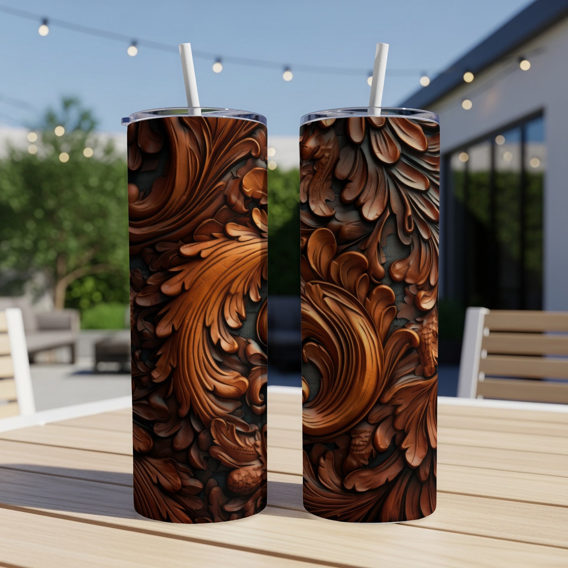 Two ornate, carved wood-style tumblers with straws sit on a wooden table outdoors.