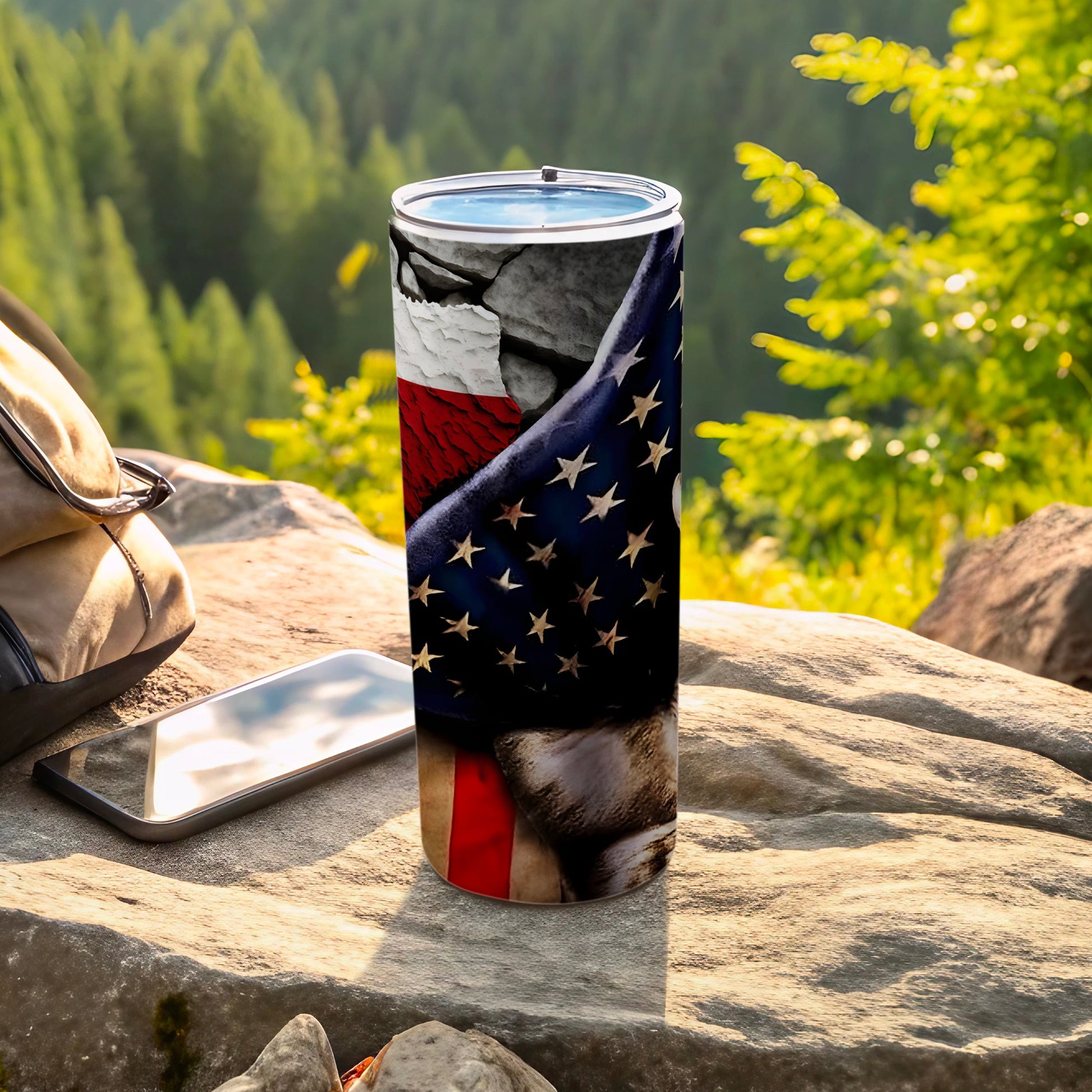 Tumbler with American flag design and rocky texture, resting on rocks outdoors.