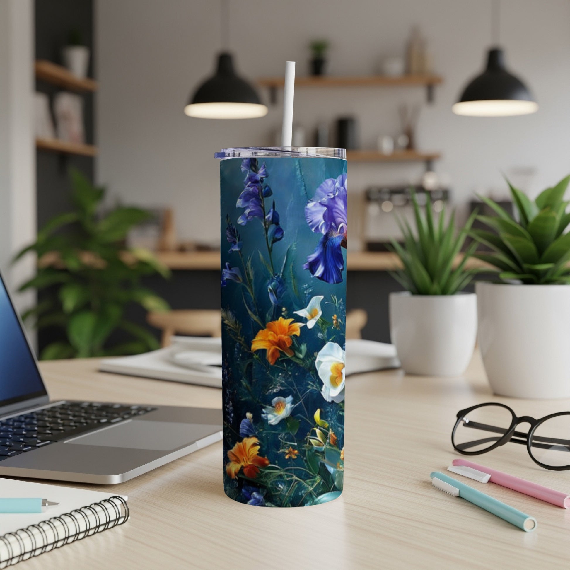 Floral patterned tumbler with straw on a wooden desk.